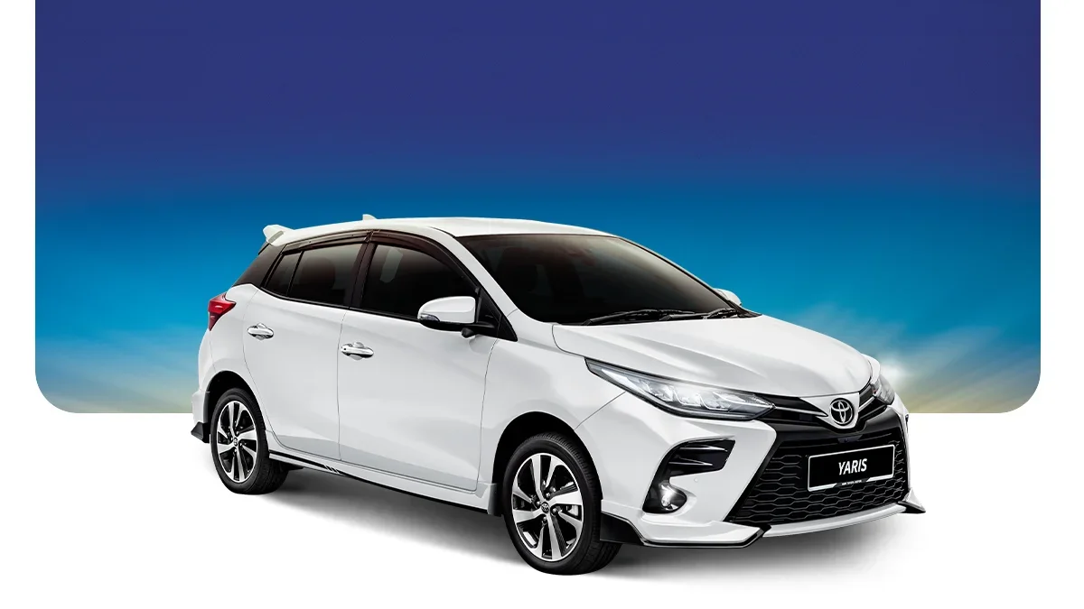 White Toyota Yaris car with black-tinted windows, set against a background that transitions from blue sky to a pale horizon.