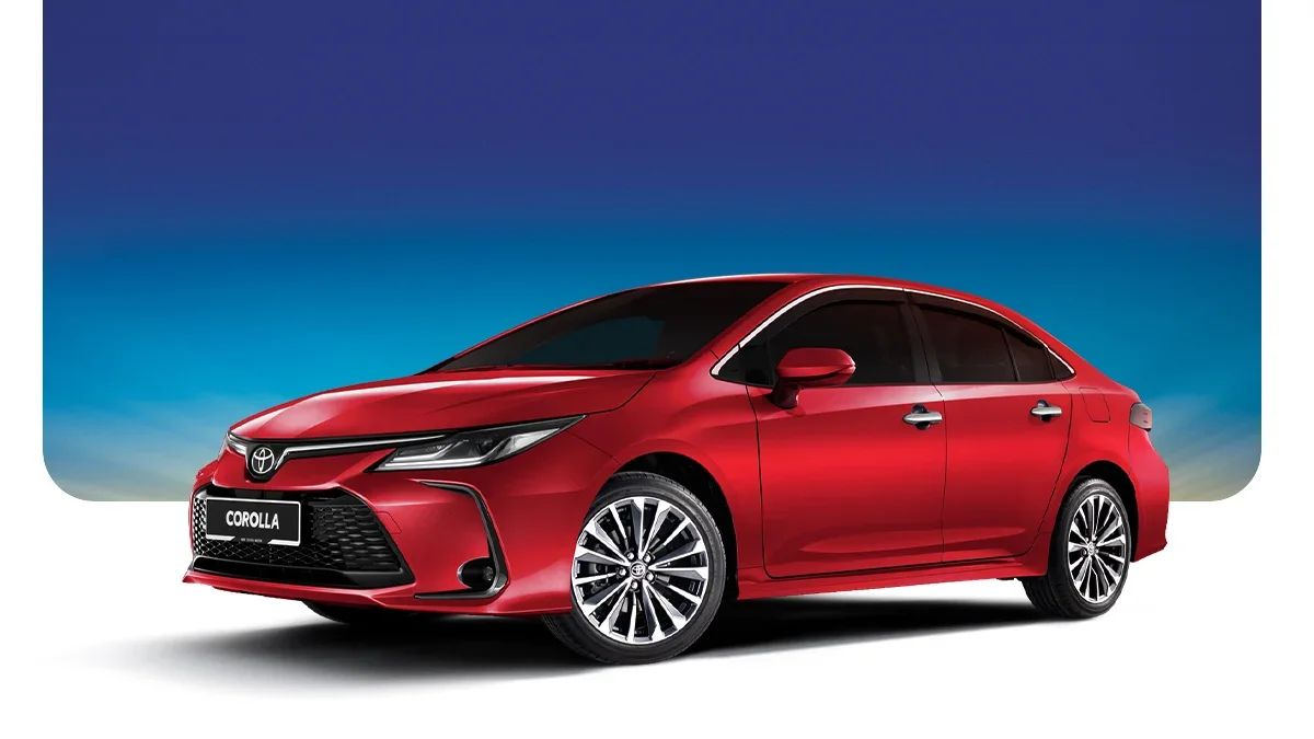 Red Toyota Corolla sedan with black tinted windows, alloy wheels, and modern design, parked against a landscape background with a gradient sky.