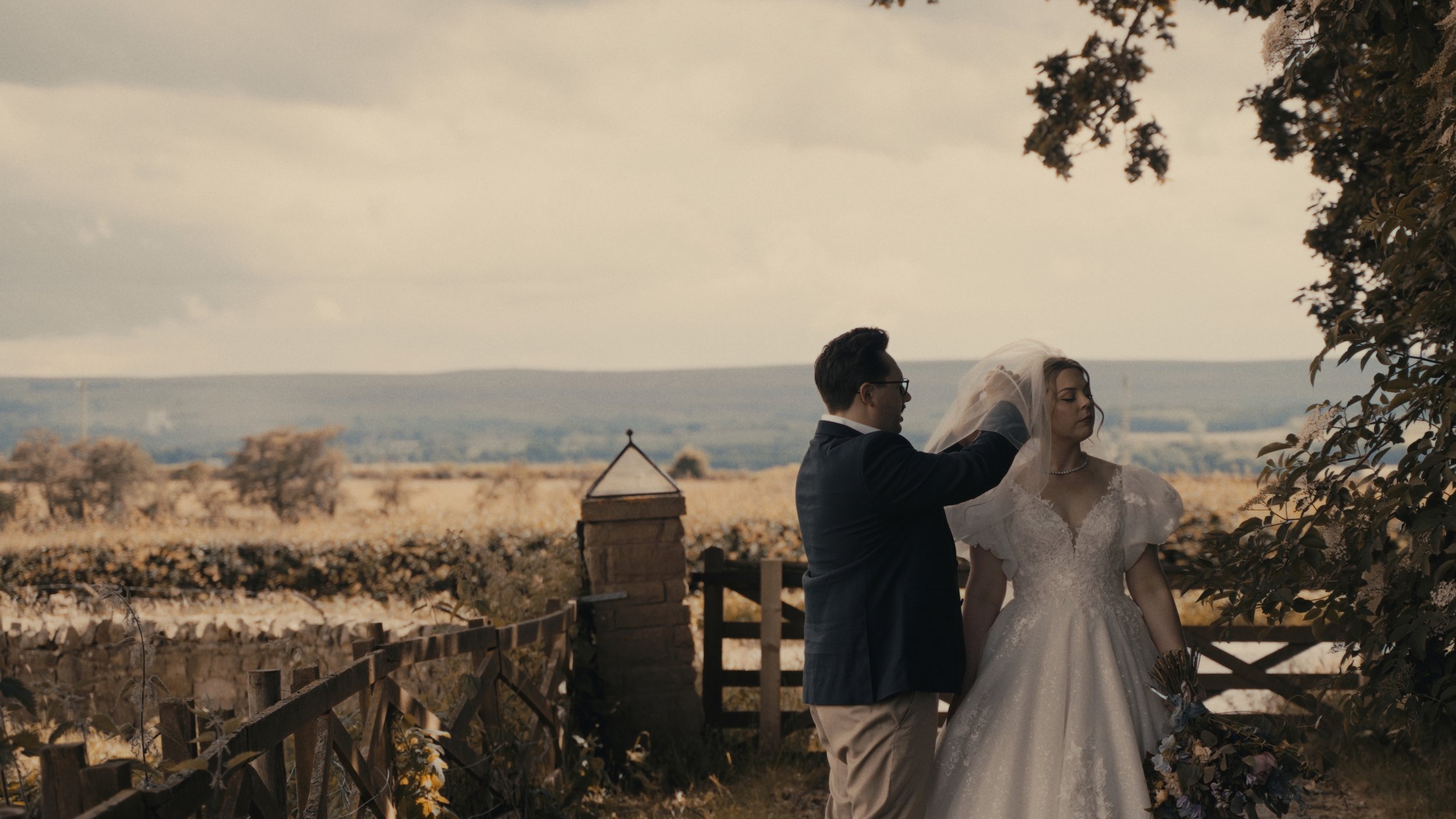 Groom fixing brides vail with countryside in the background