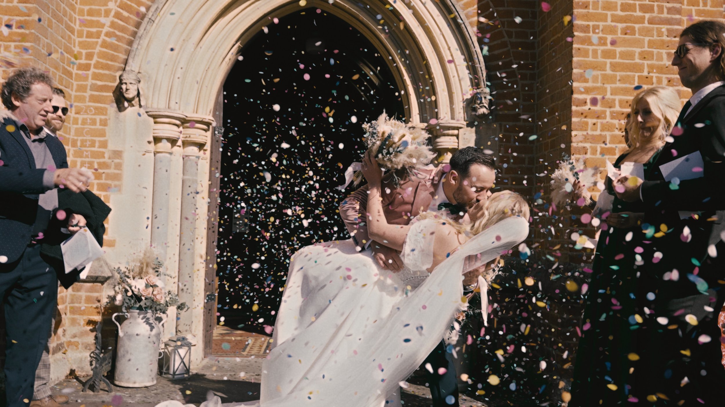 Bride and groom getting confetti thrown at them outside a church