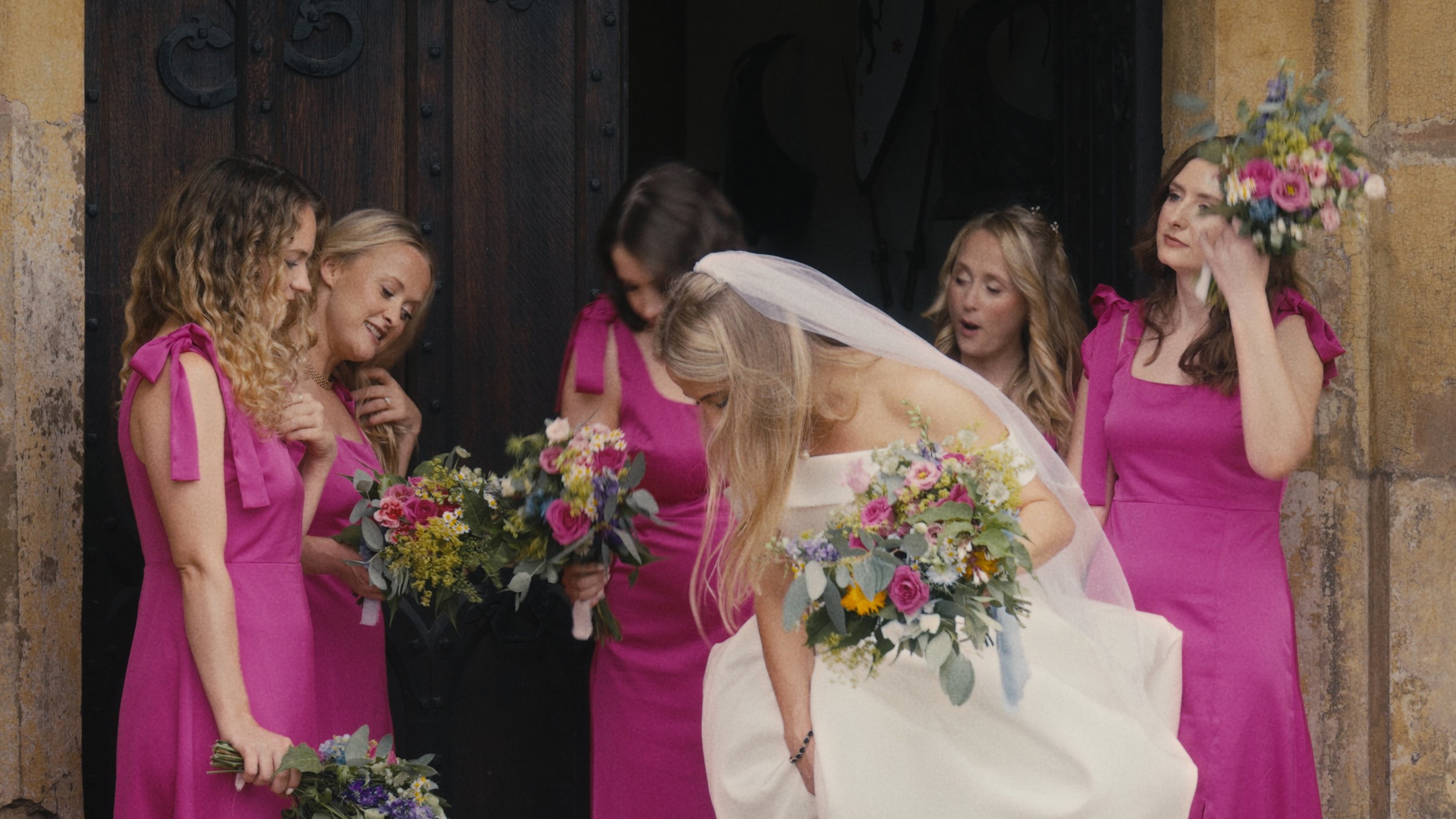 Bridesmaids looking at brides dress in a doorway.