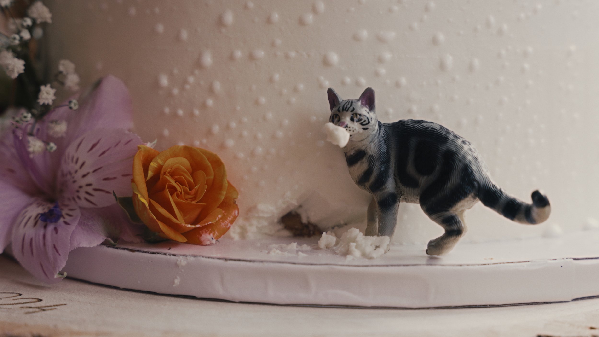 Wedding cake with cat figure eating the side of it.