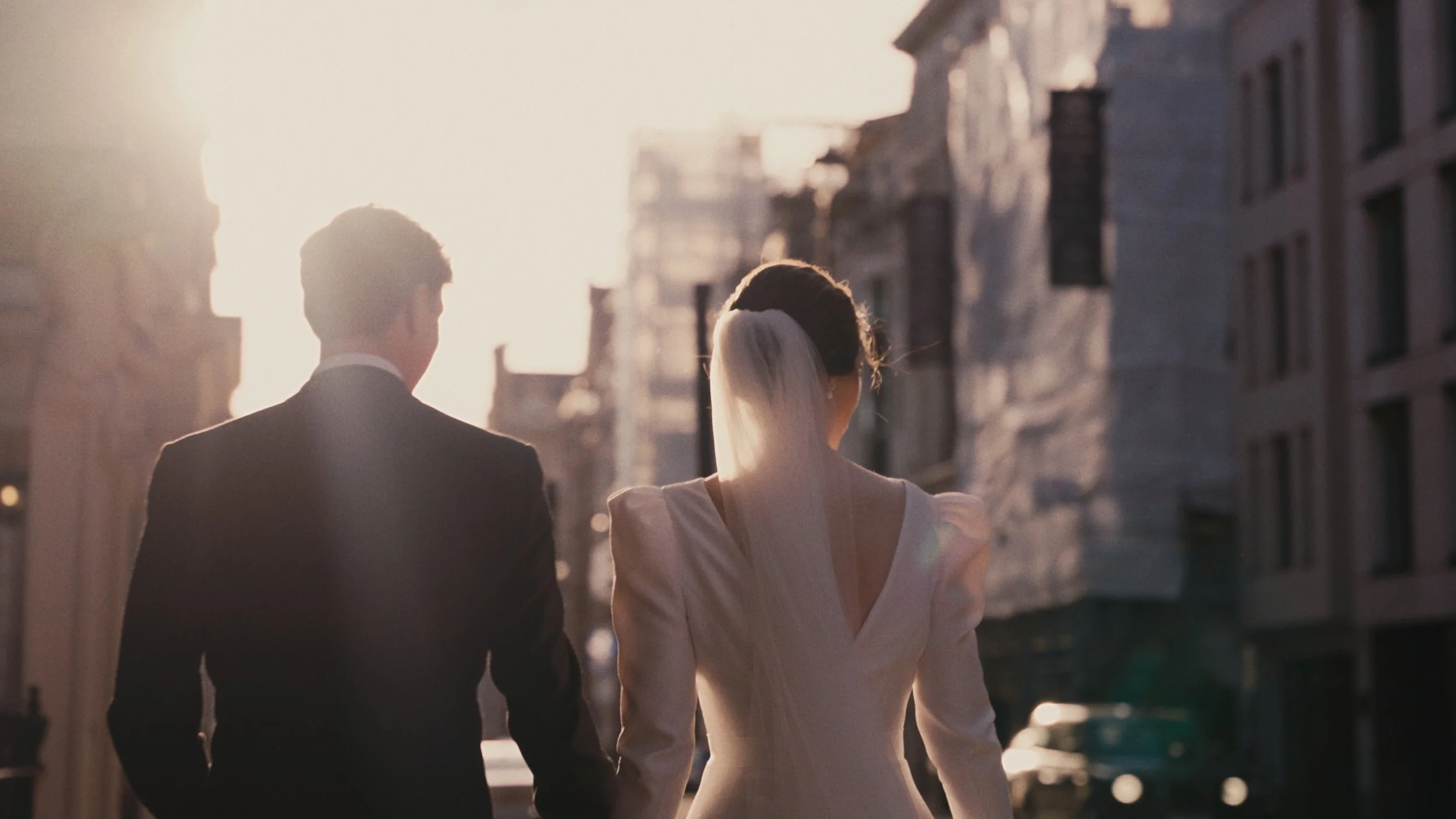 Bride and groom walking down London street with sun shining