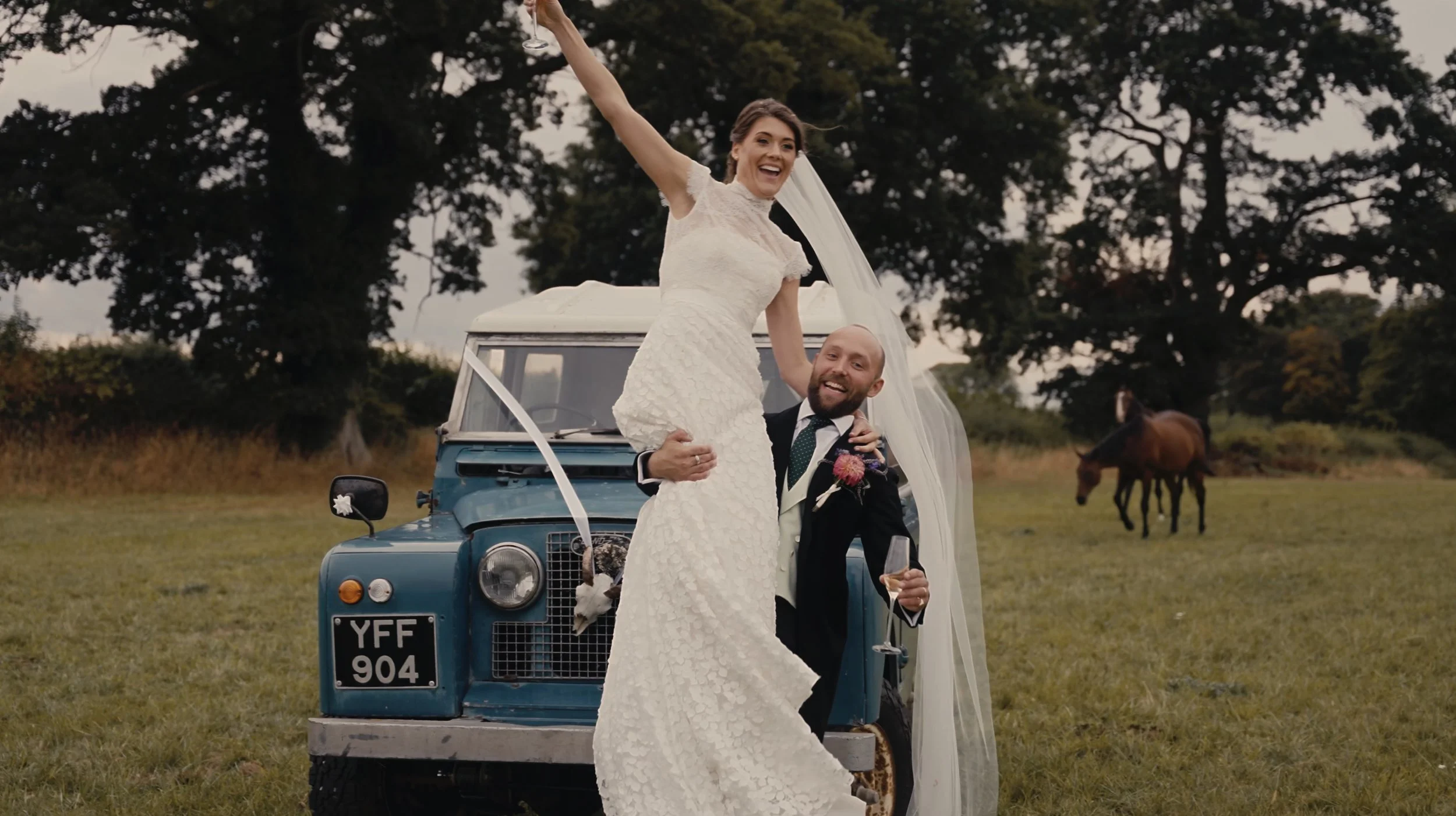 Groom picking up bride in front of car