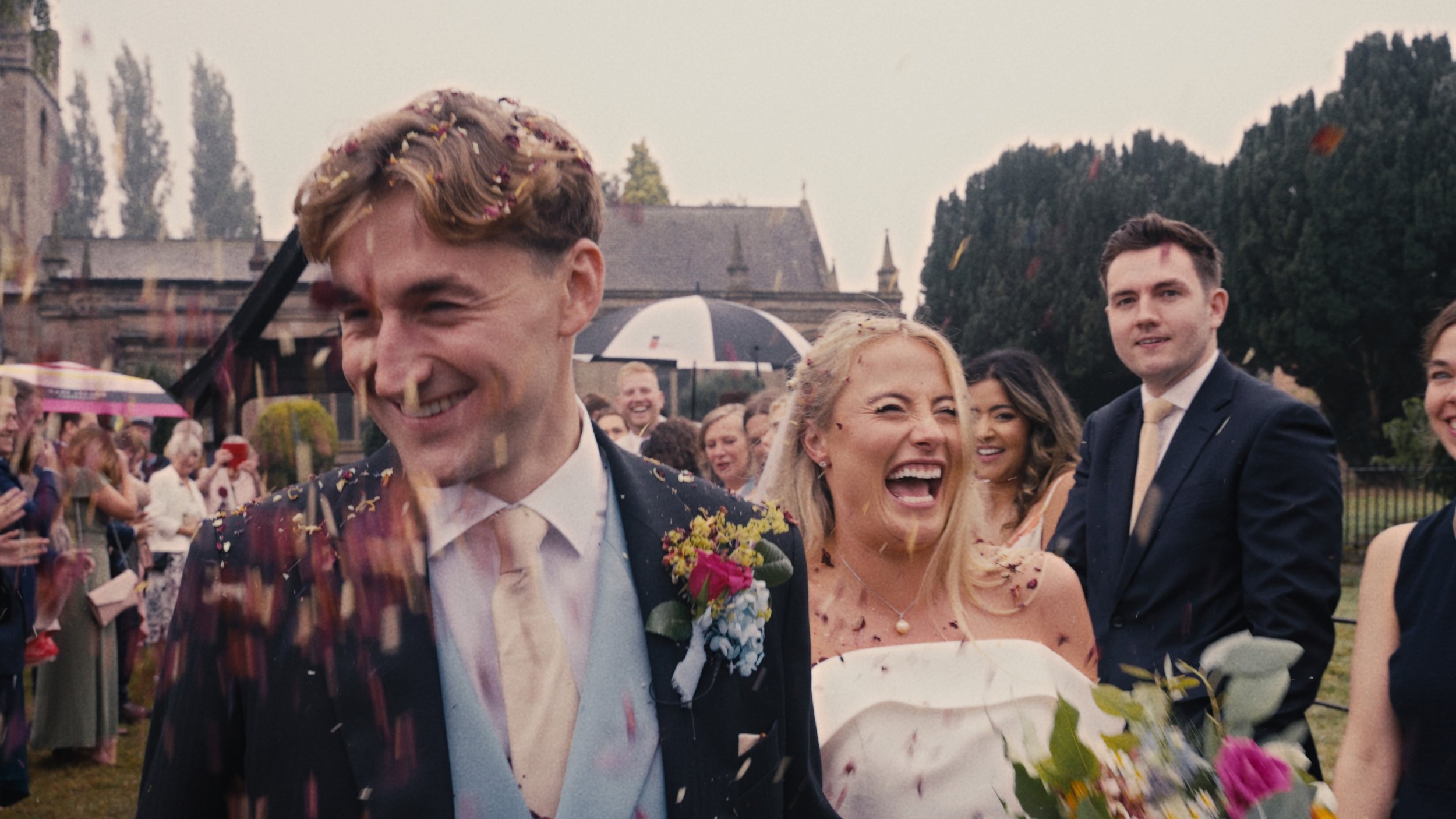 Bride and groom smiling as confetti is being thrown.