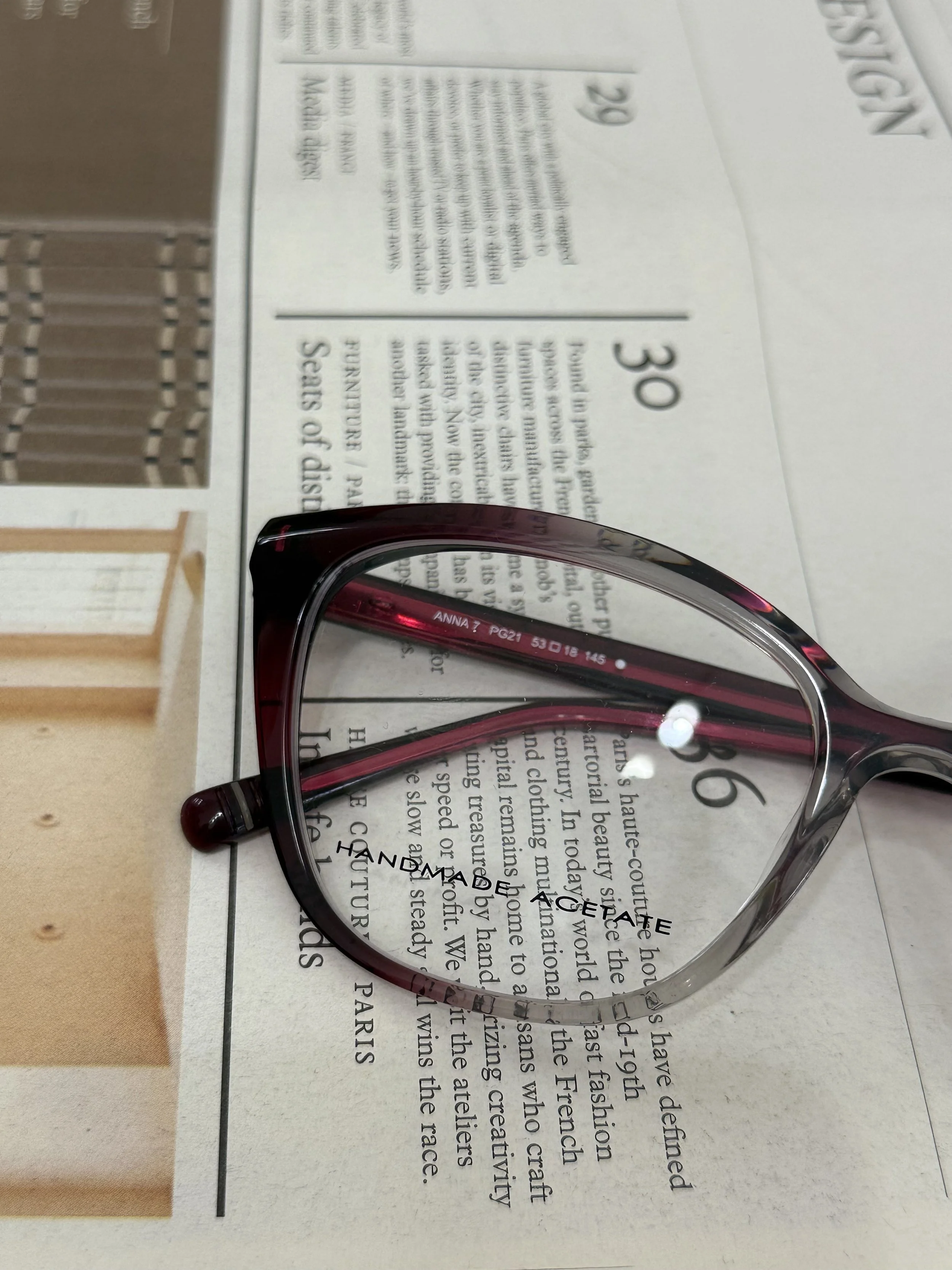 A pair of Morel glasses placed on a newspaper with text. Morel szemüvegkeret a Showroom Optikában Budapesten egy Monocle újságon. 