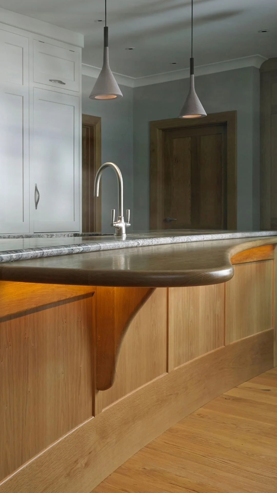 Close-up of curved bespoke kitchen island showcasing handmade joinery and smooth oak finish.