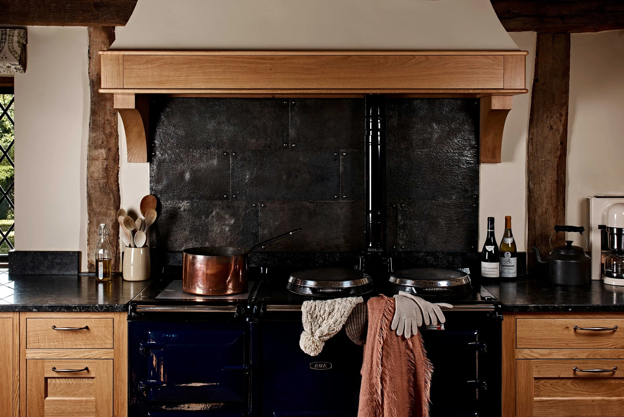 Black Aga with hidden handmade spice storage and forged iron splashback in Surrey kitchen.