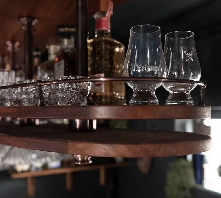 Close-up of handmade curved bar gantry designed for hanging glass storage in London home bar.