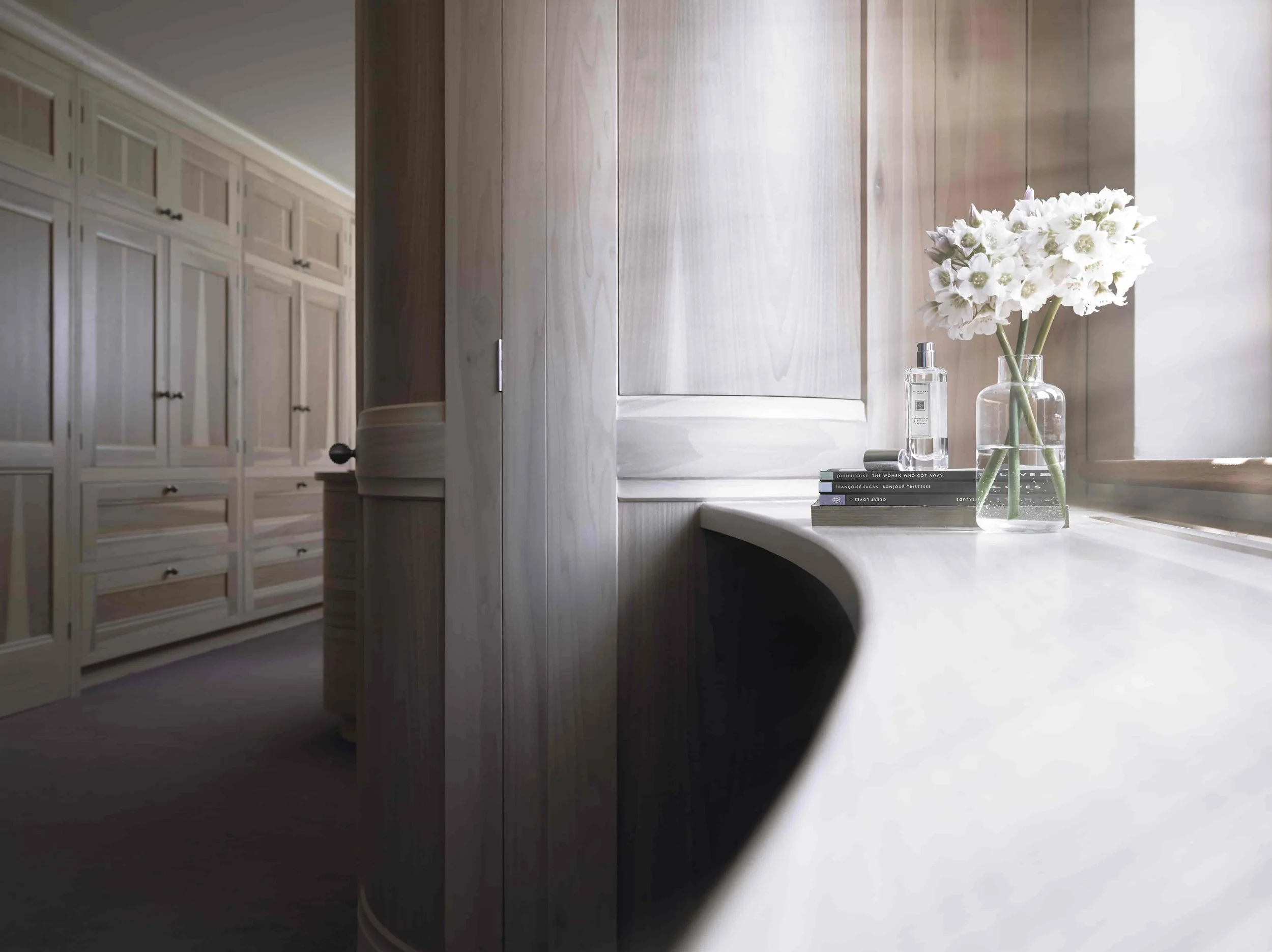 Curved bedroom cabinetry with handcrafted tulip wood wardrobes in bespoke interior design.