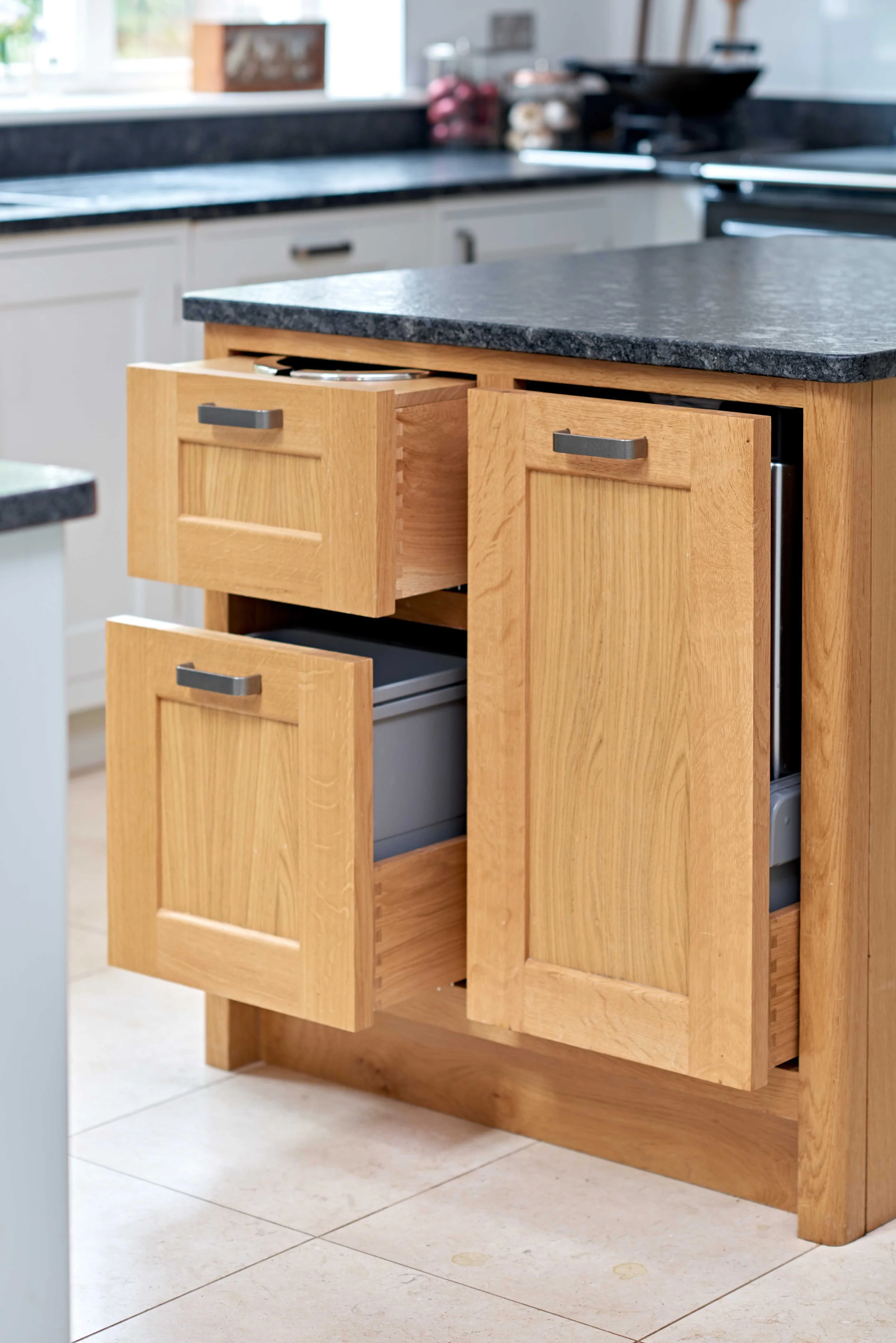 Handmade oak kitchen island with integrated veg bins and storage in Guildford home.