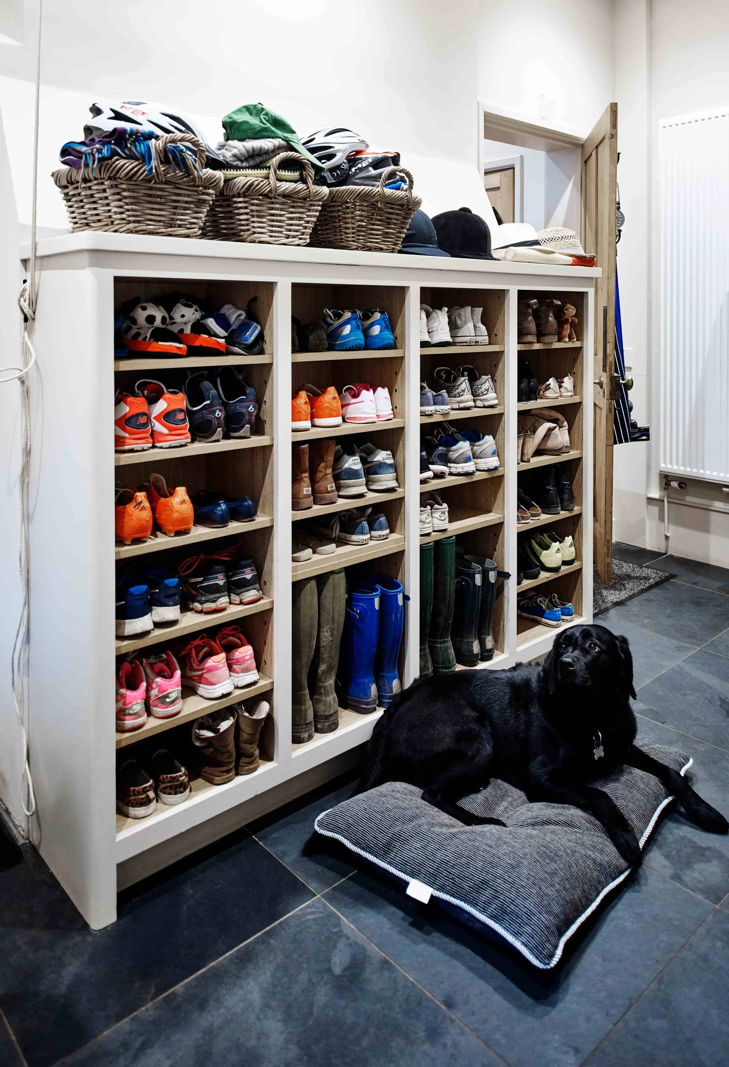 Practical handmade boot room storage in a Surrey family home with black Labrador.