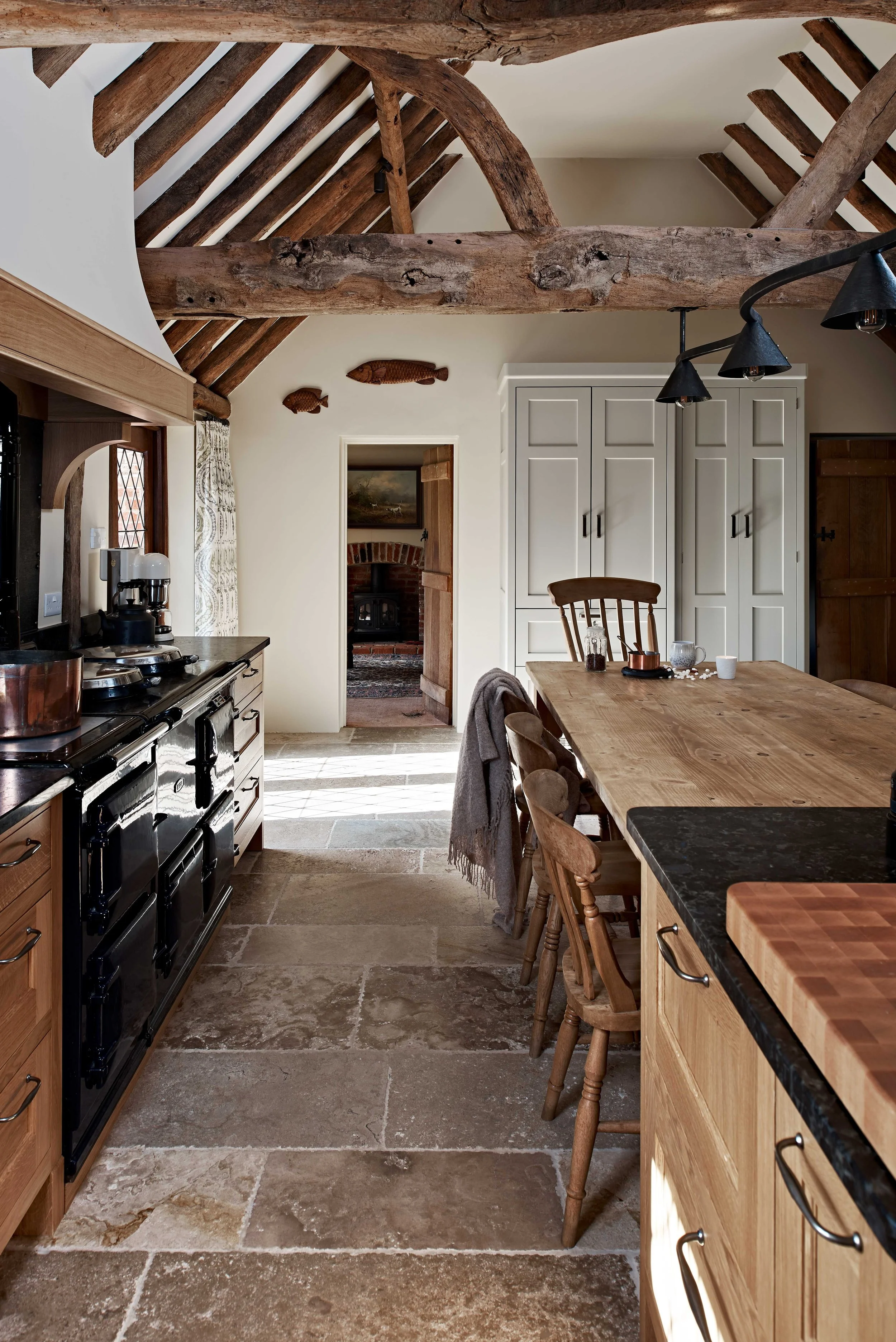Beamed farmhouse kitchen in Surrey with black Aga, handmade cabinetry and family table.