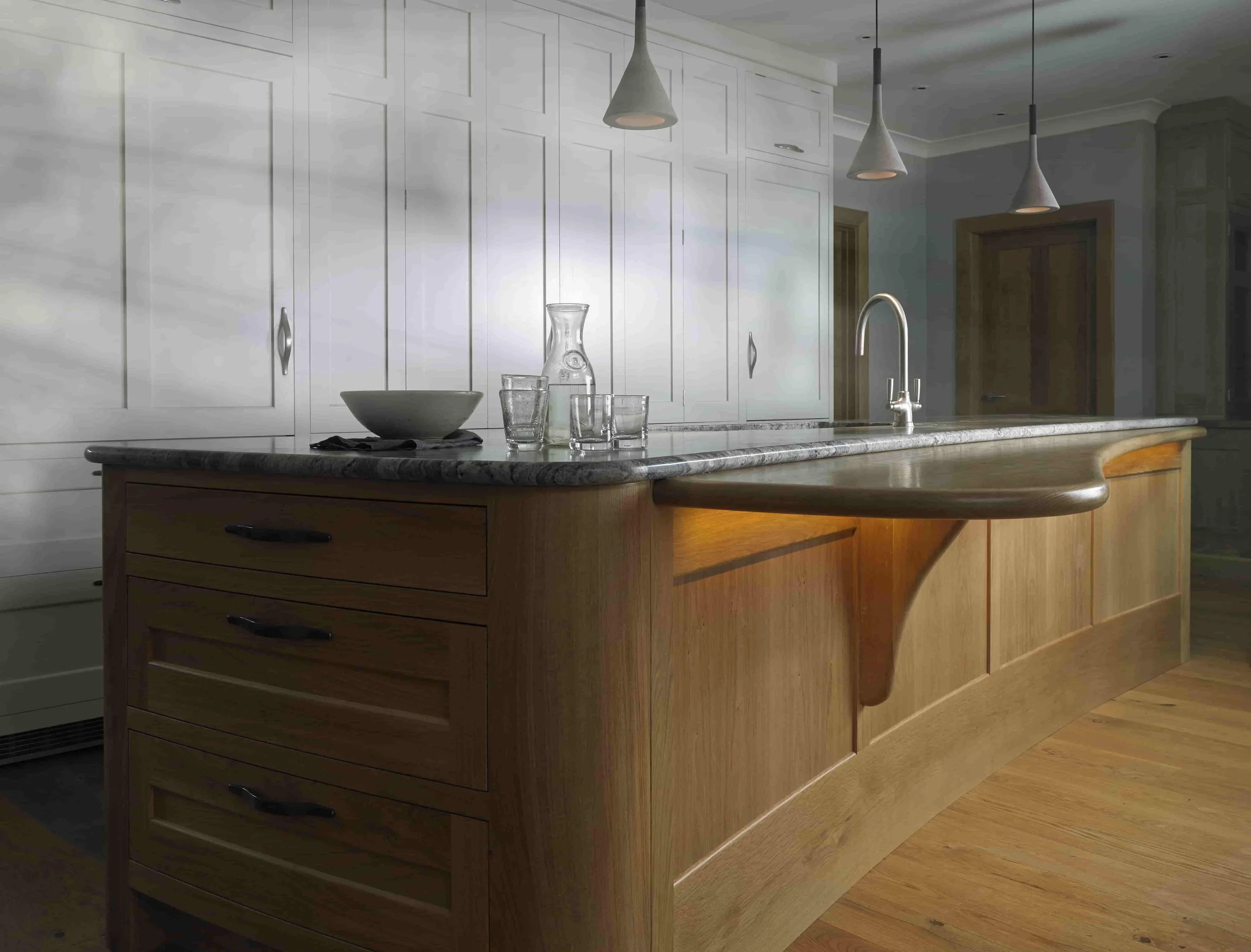 Bespoke handcrafted oak curved kitchen island with custom-made detailing in luxury country kitchen.