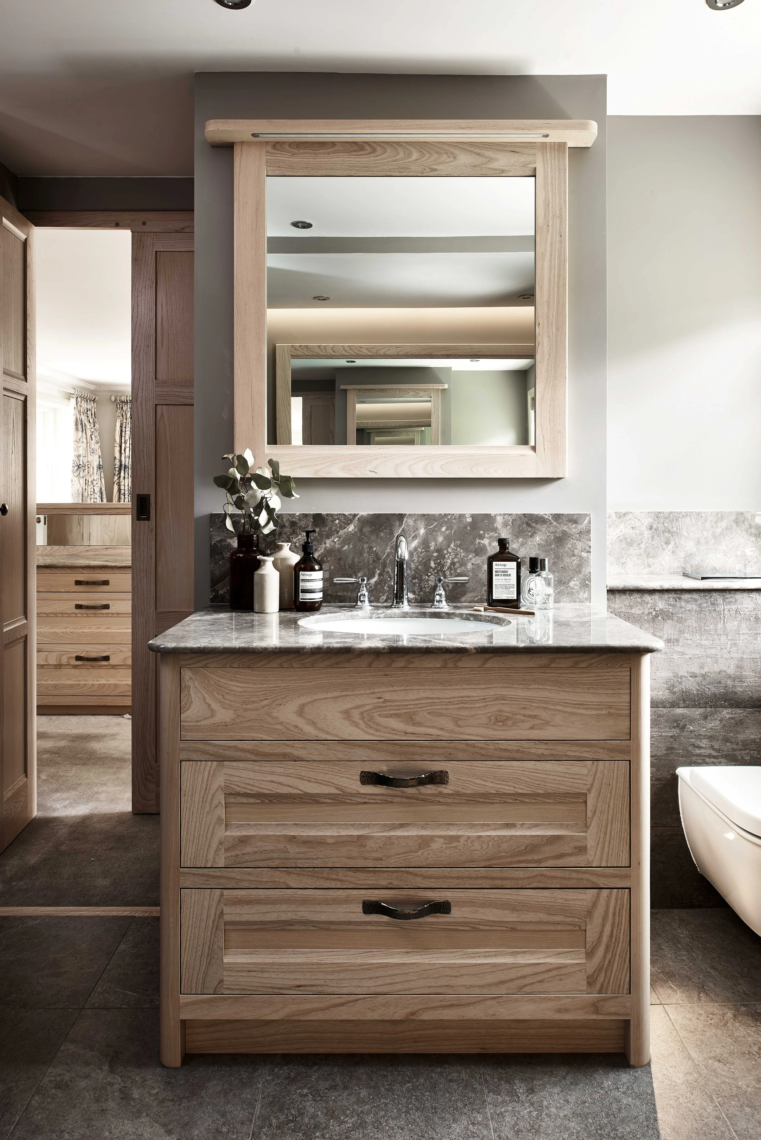Bespoke handcrafted oak bathroom cabinetry with matching oak framed mirror.