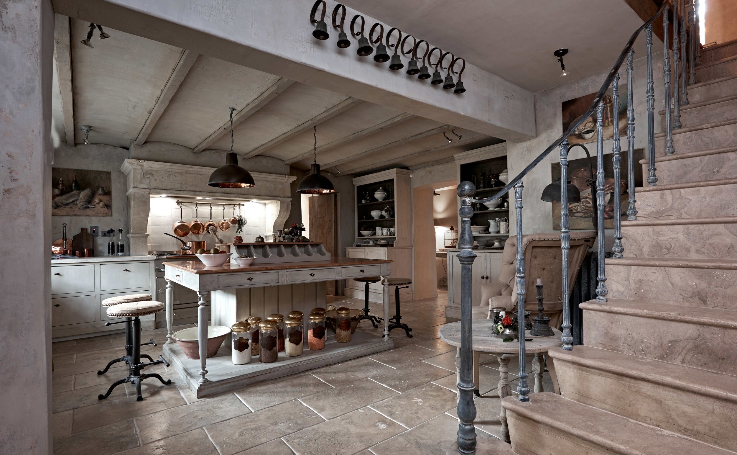 Lower-ground handmade kitchen in London with limestone floor, stone stairs and bespoke island.