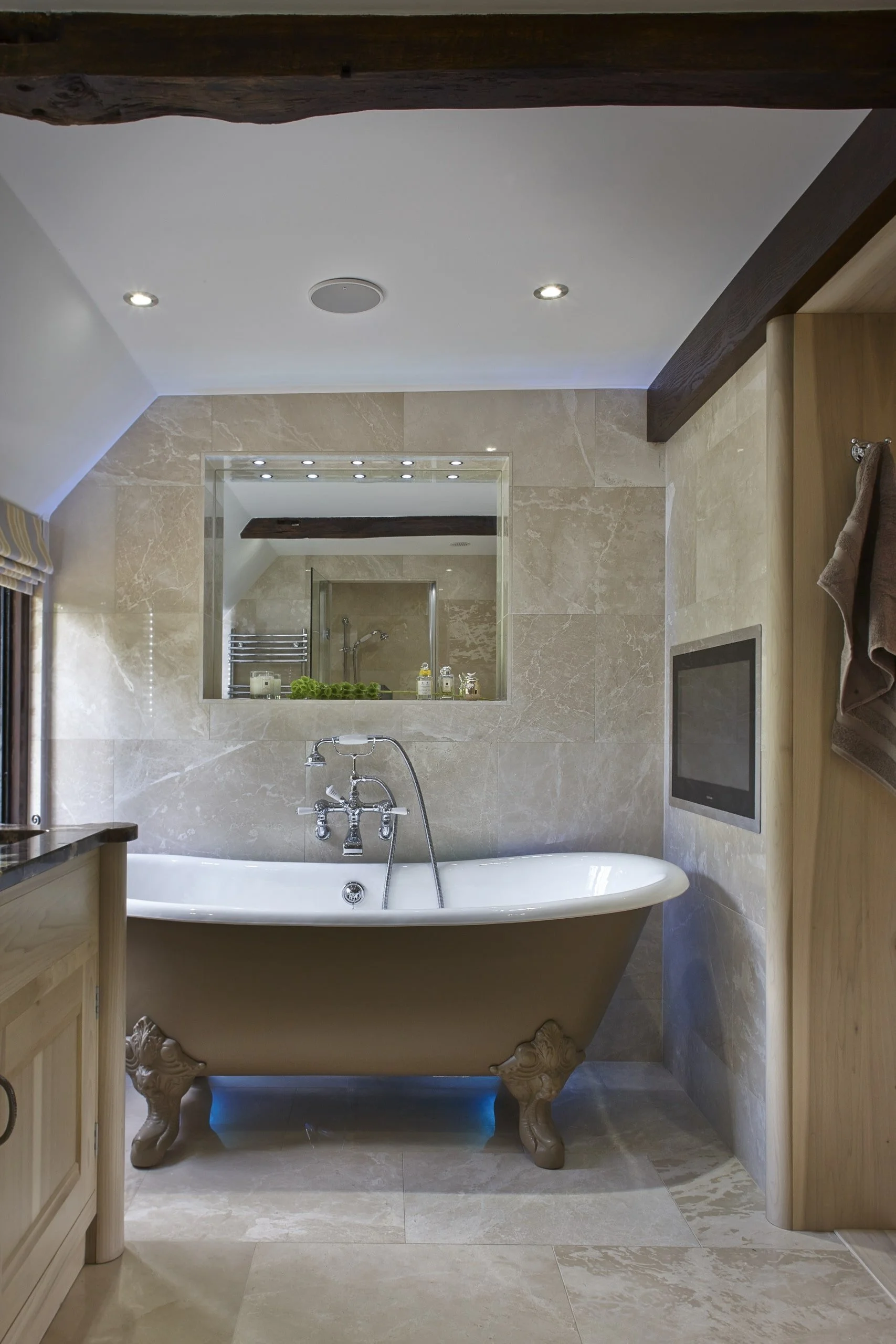 Luxury Surrey master en-suite with handmade cabinetry, roll-top claw-foot bath and built-in TV.