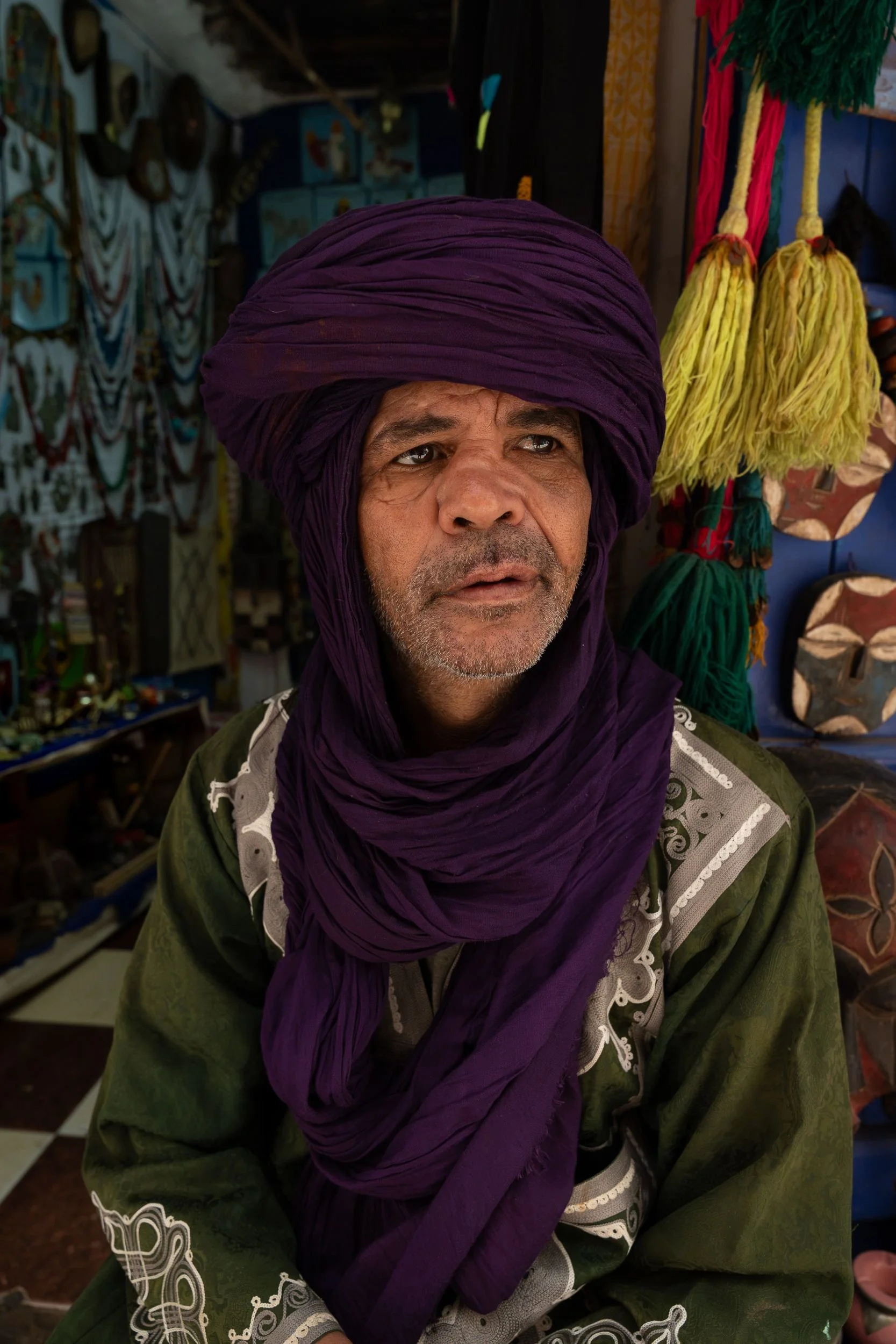 A market vendor wearing a purple headscarf outside his stall in Essaouira, Morocco.