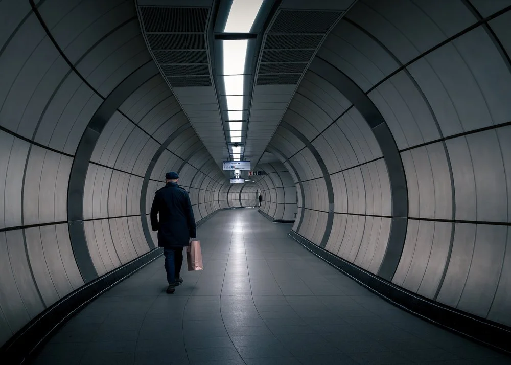 man walking down tunnel in a London tube station classic Elizabeth line decor