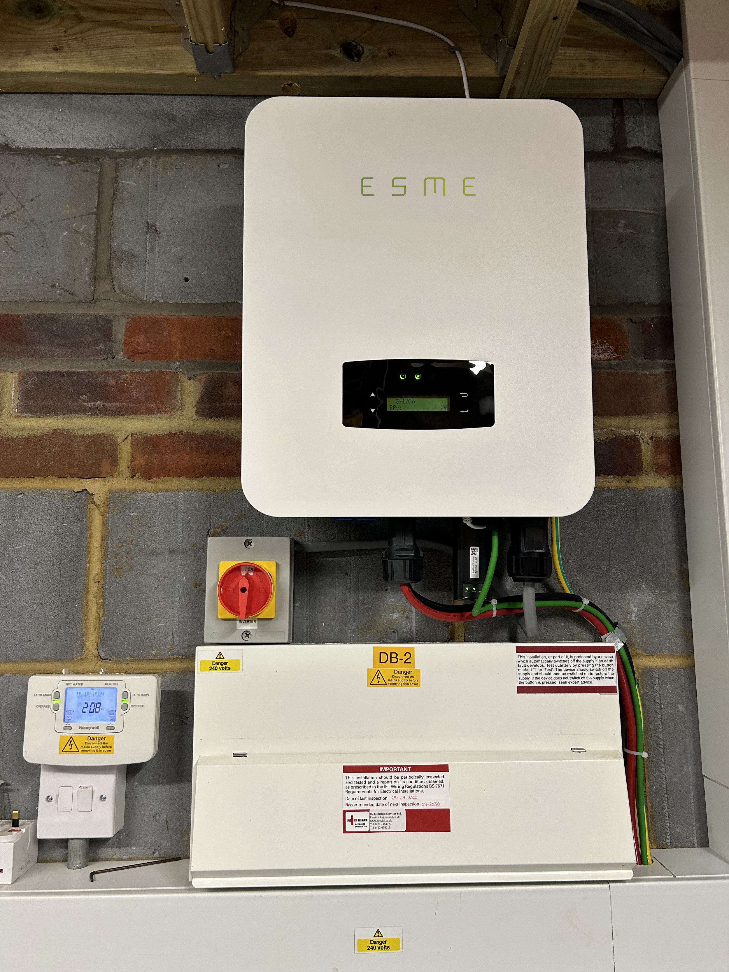 Electrical equipment with a box labeled "ESME," a power switch, wiring, and an electrical meter on a wall.