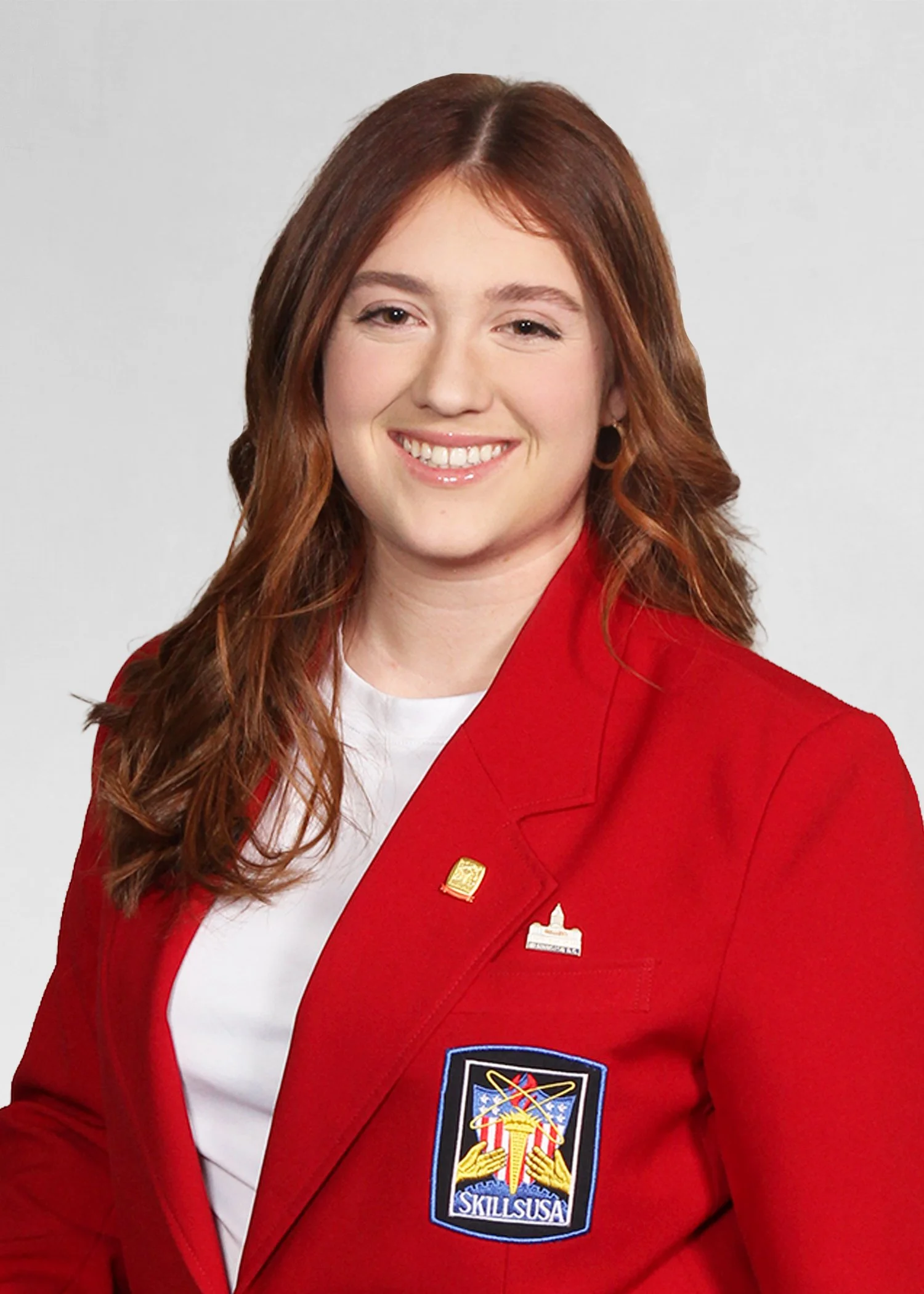 A young woman smiling outdoors, wearing a navy blue jacket with 'STATE OFFICER' and 'SkillUSA MASSACHUSETTS' embroidered on it.