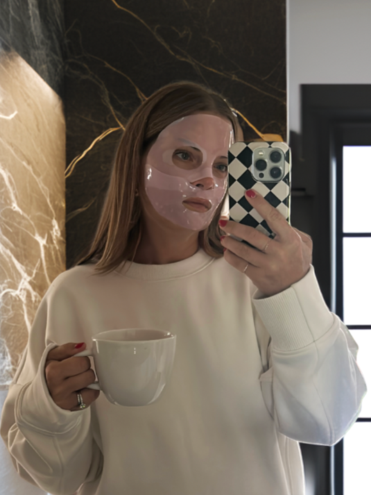 Girl wearing face mask holding coffee cup and phone