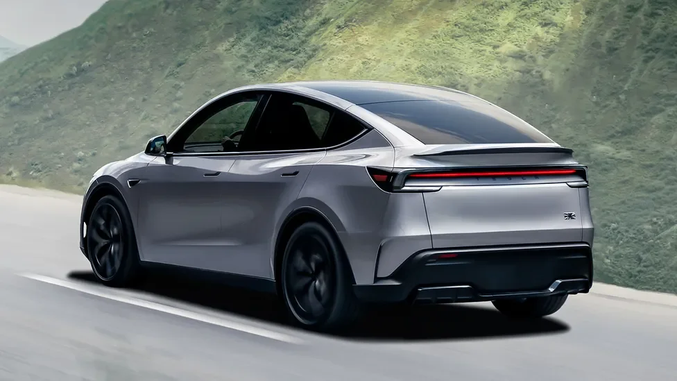 A sleek silver electric car driving on a two-lane road with greenery on the hillside in the background.
