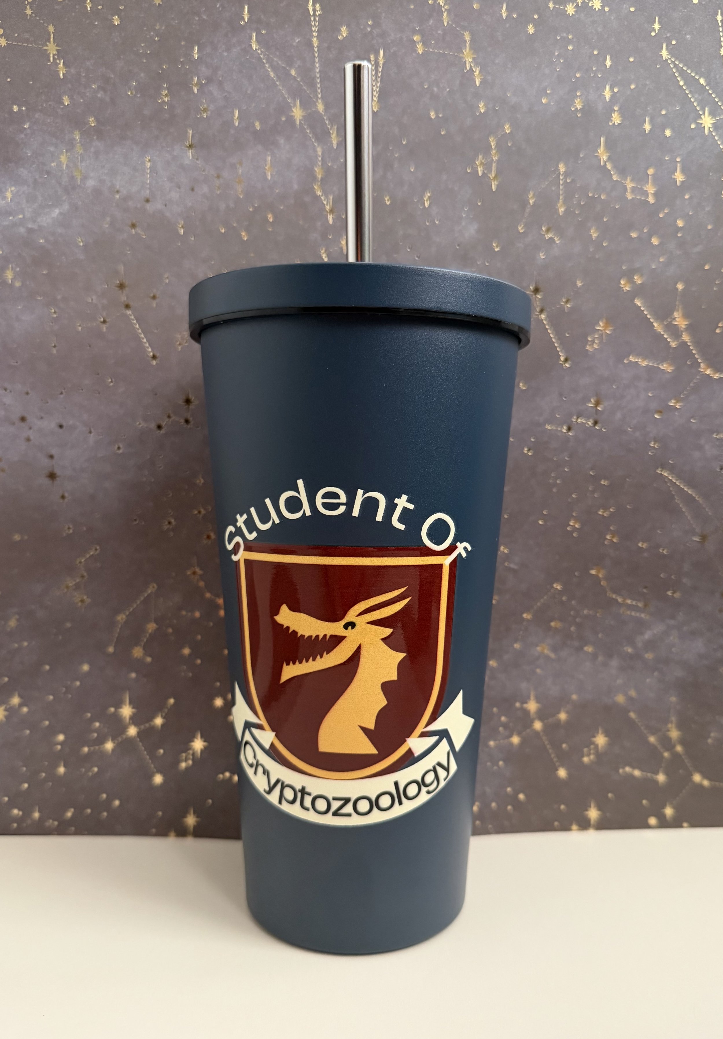 Student of Cryptozoology Cryptid Crest on blue tumbler with straw.jpeg