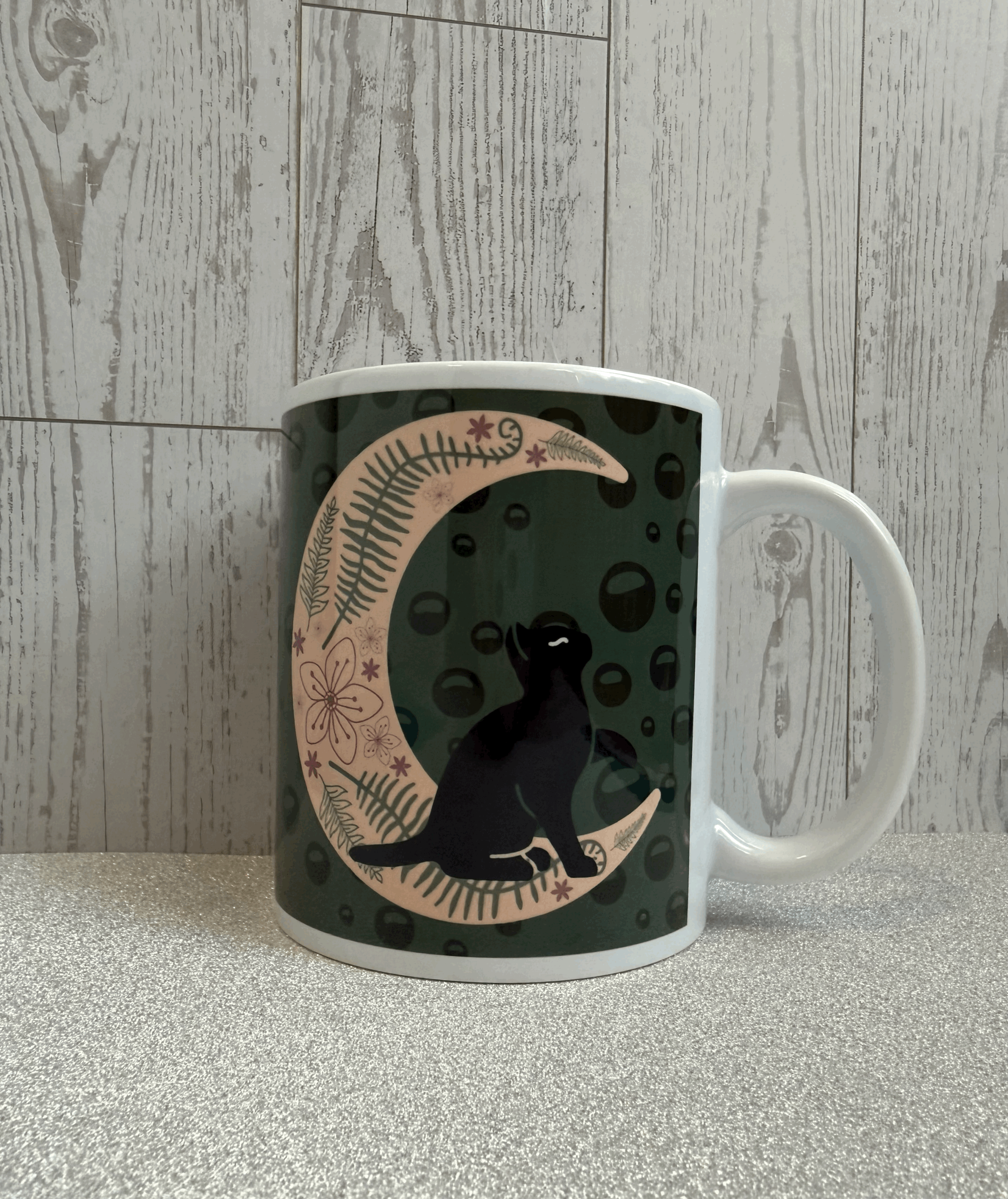 spring black cat and moon themed coffee mug with ferns and pink wildflowers.gif