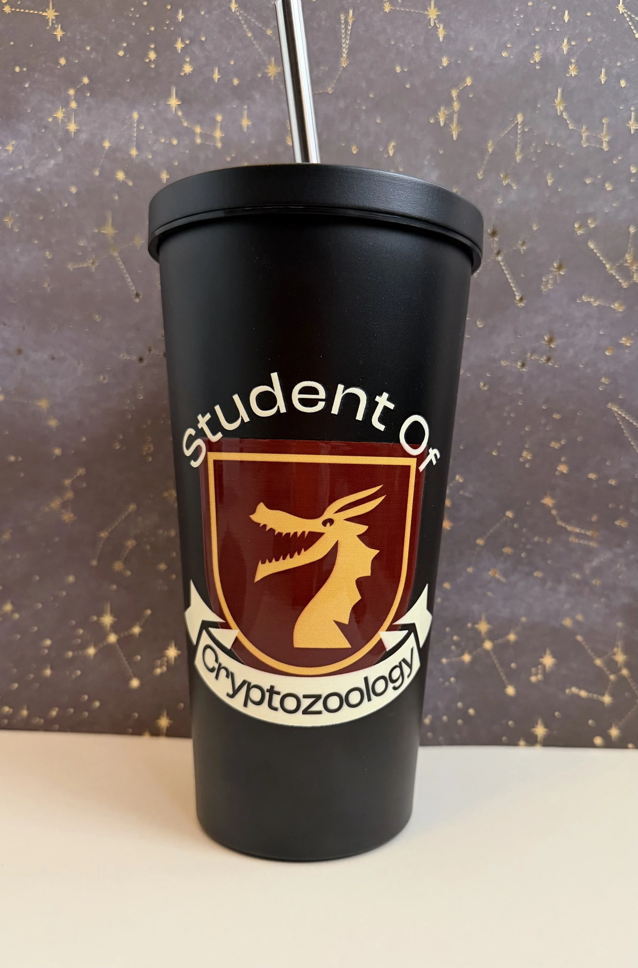 Student of Cryptozoology with crest on black tumbler with straw.jpeg