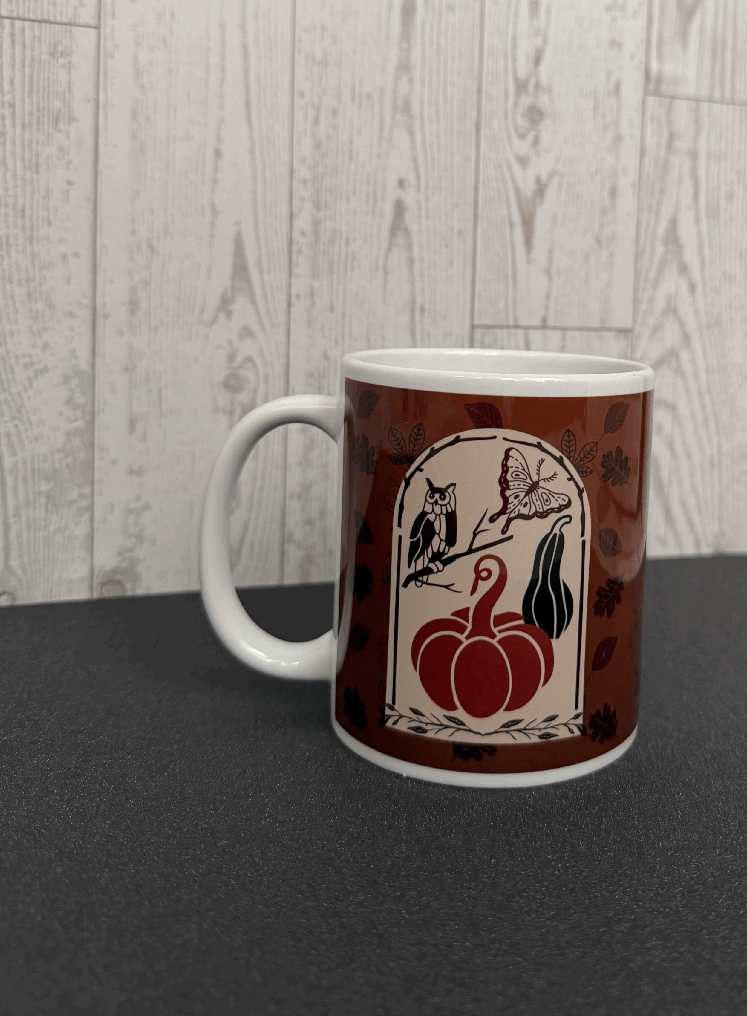 Autumn themed mug featuring a rustic framed image of a collection of fall items: a moth, an owl, a pumpkin, and a gourd.gif