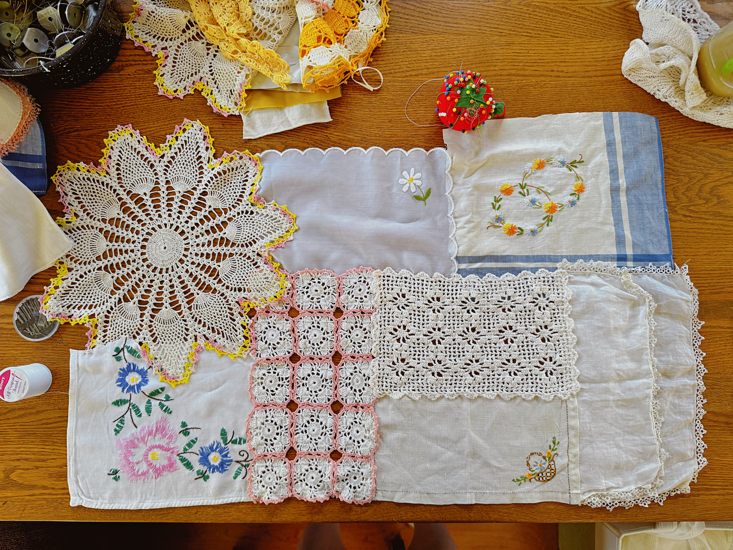 A small curtain made from scraps of table cloths, doilies, and cloth napkins laying on a table.