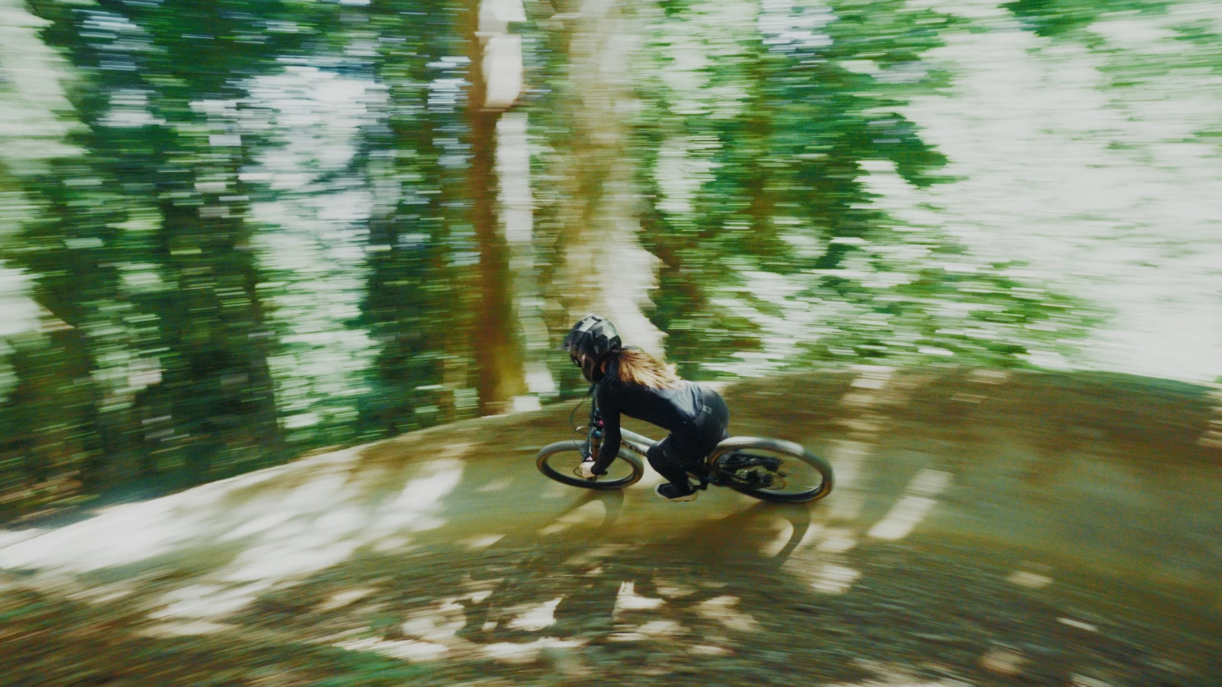 Etalonnage de Kevin Rocha. Une personne en casque de protection fait du VTT sur un sentier forestier, angle dynamique.