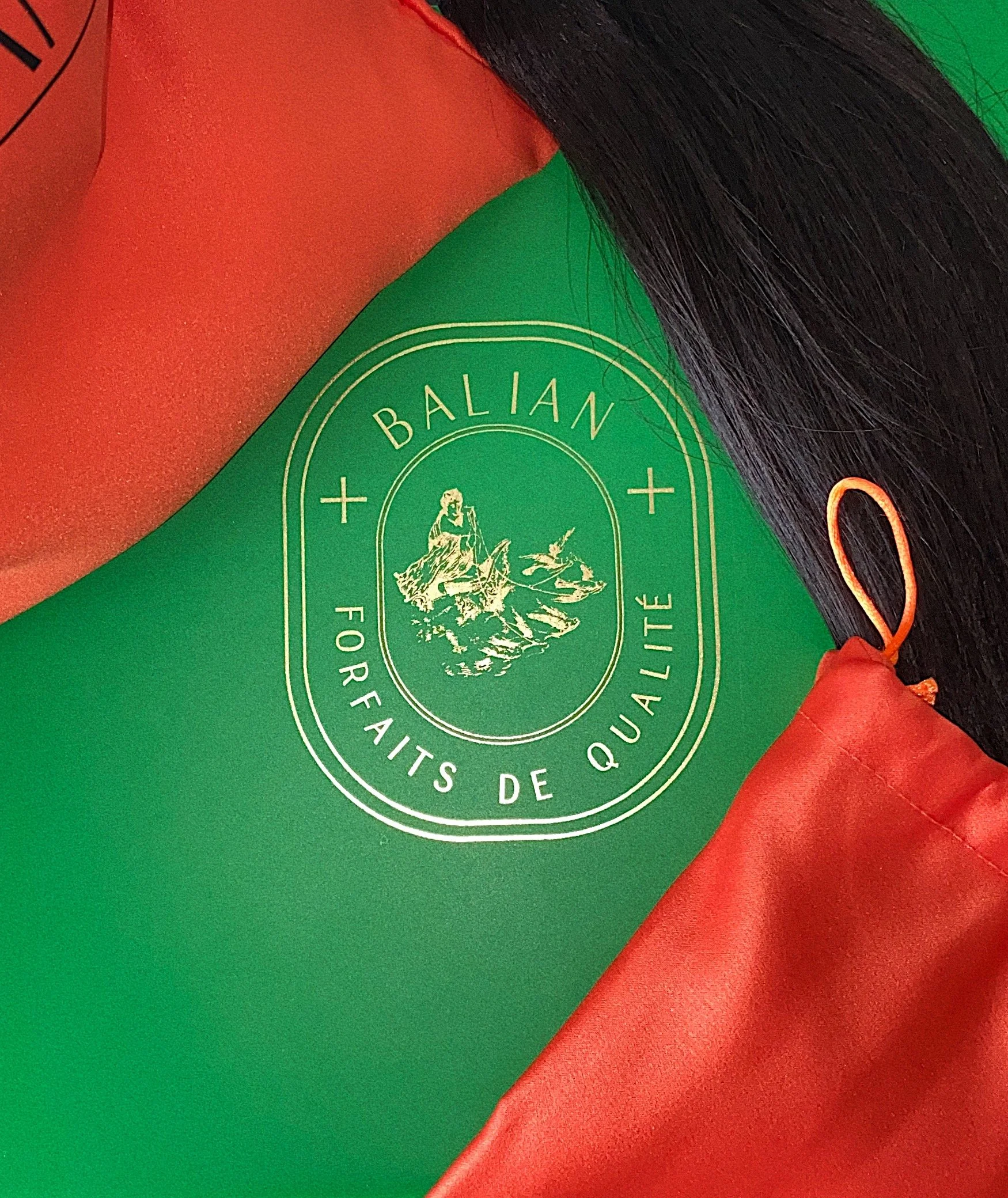 Close-up of a green and orange jacket with a badge that reads 'Balian' and 'Forfaits de Quailite,' featuring a figure fishing on water.
