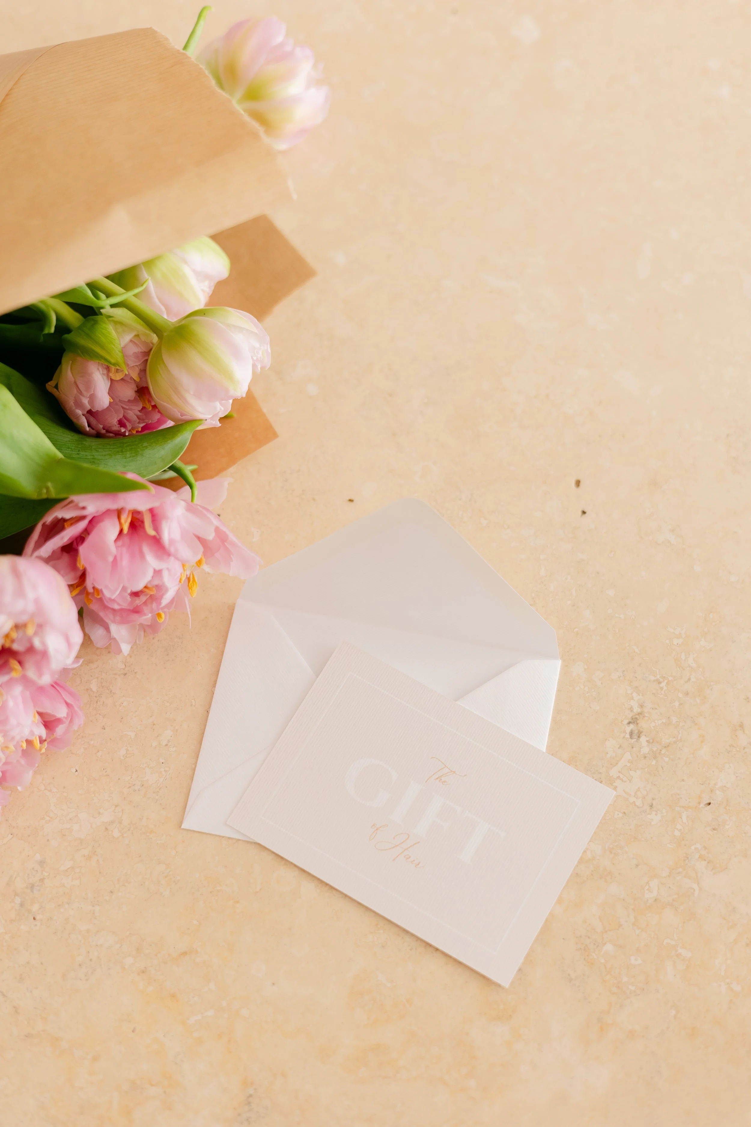 Gift voucher for 12 Trim Street, the award-winning hair salon in Bath. Accompanied by white cards and an envelope on a beige textured surface.
