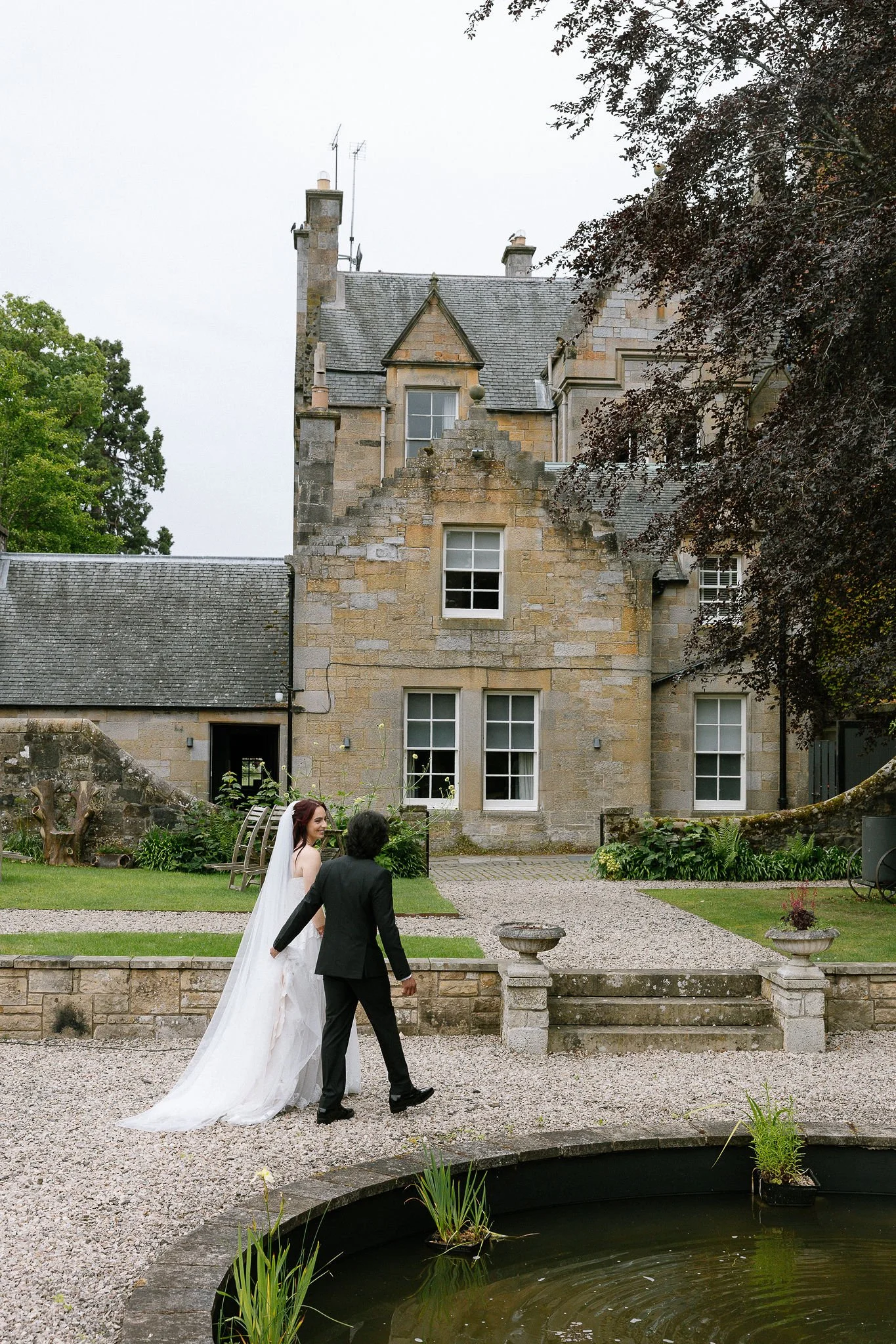 Couple is walking in front of Carlowrie castle