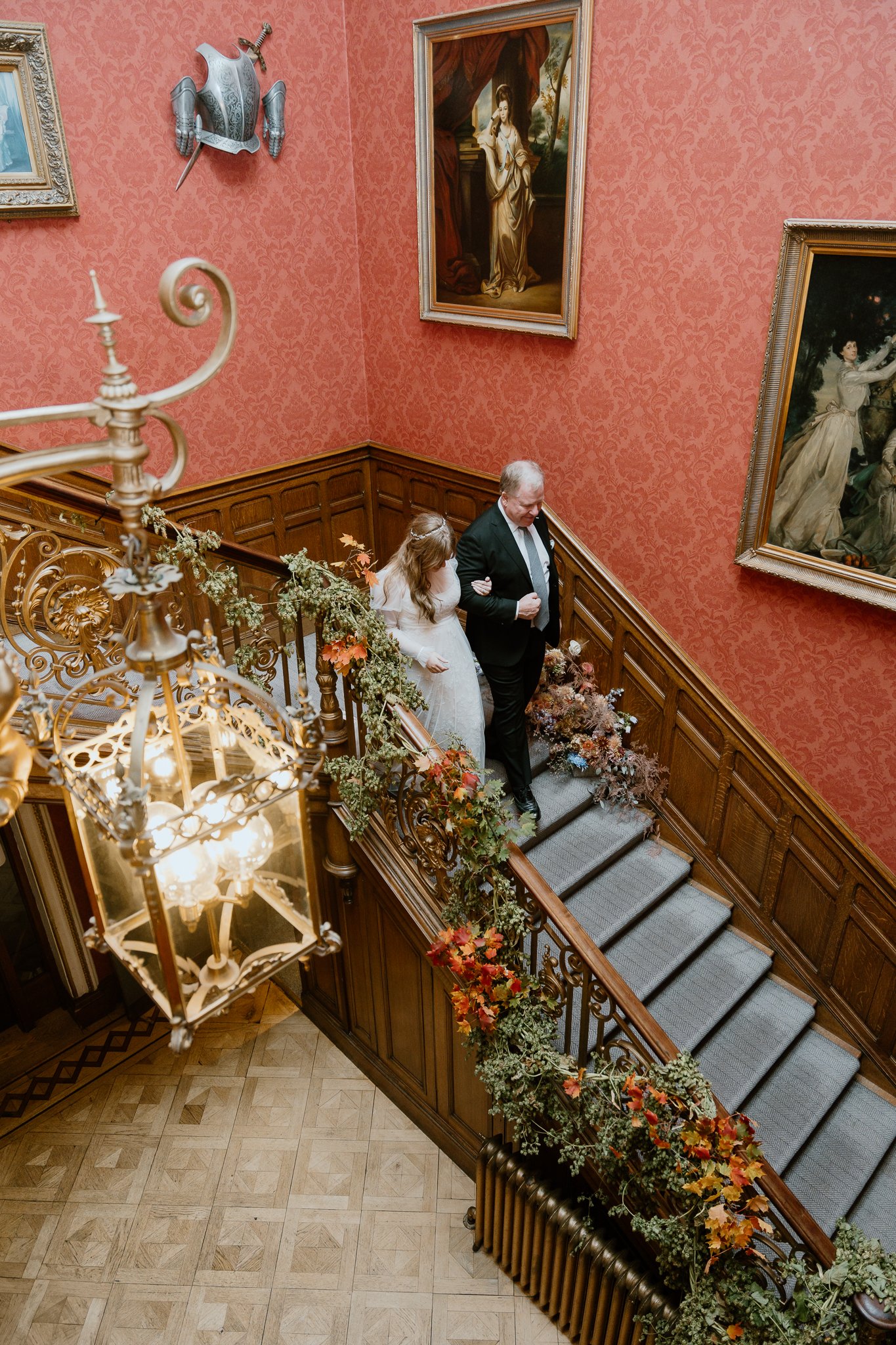 The father of the bride is walking her daughter on the grand stairs at Auchen castle. It's an American multi-day wedding celebration