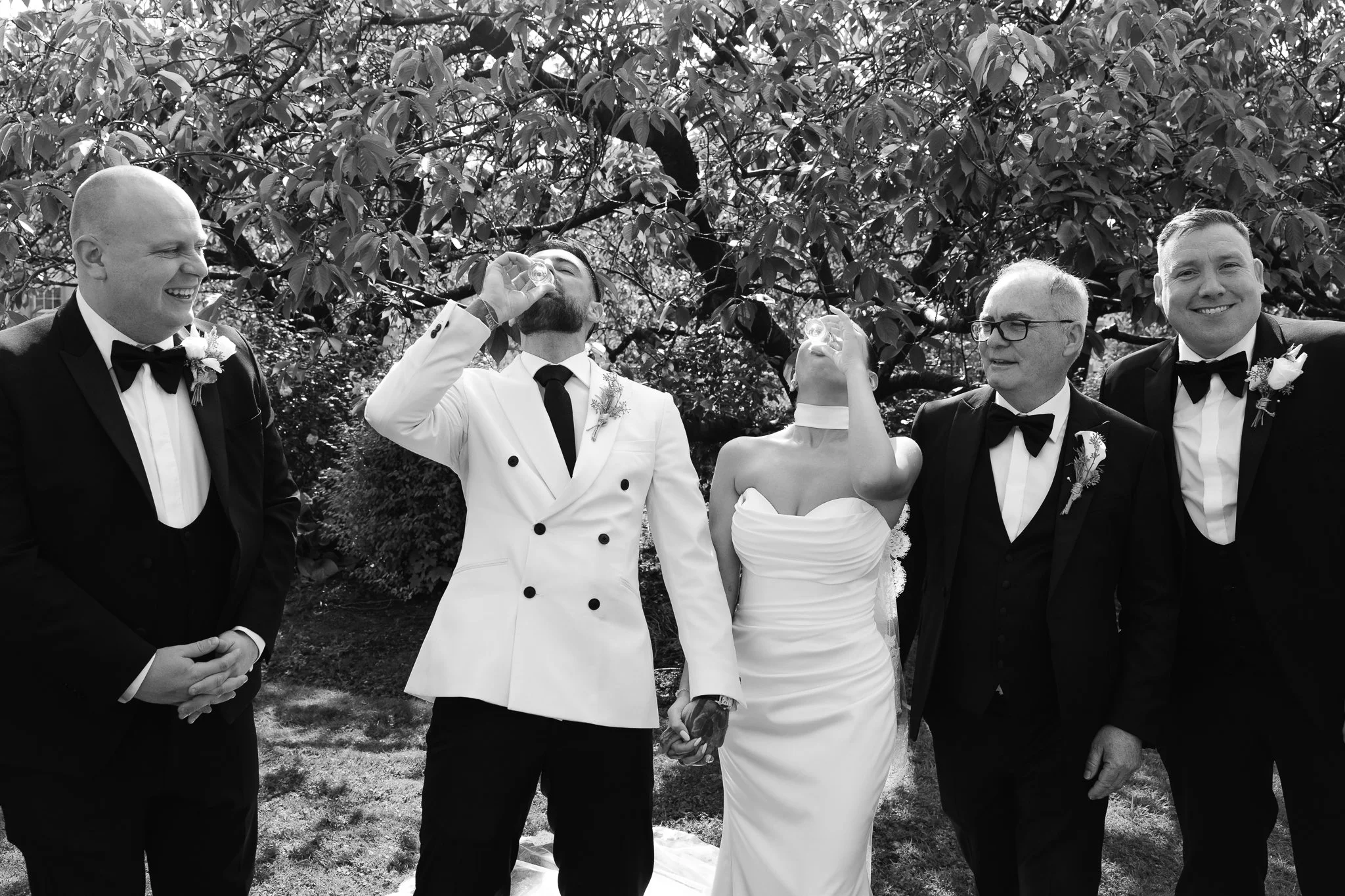 Bride and groom are drinking tequila during the group photos