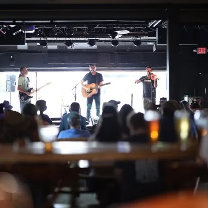 Band performing on stage with audience in a dimly lit venue.