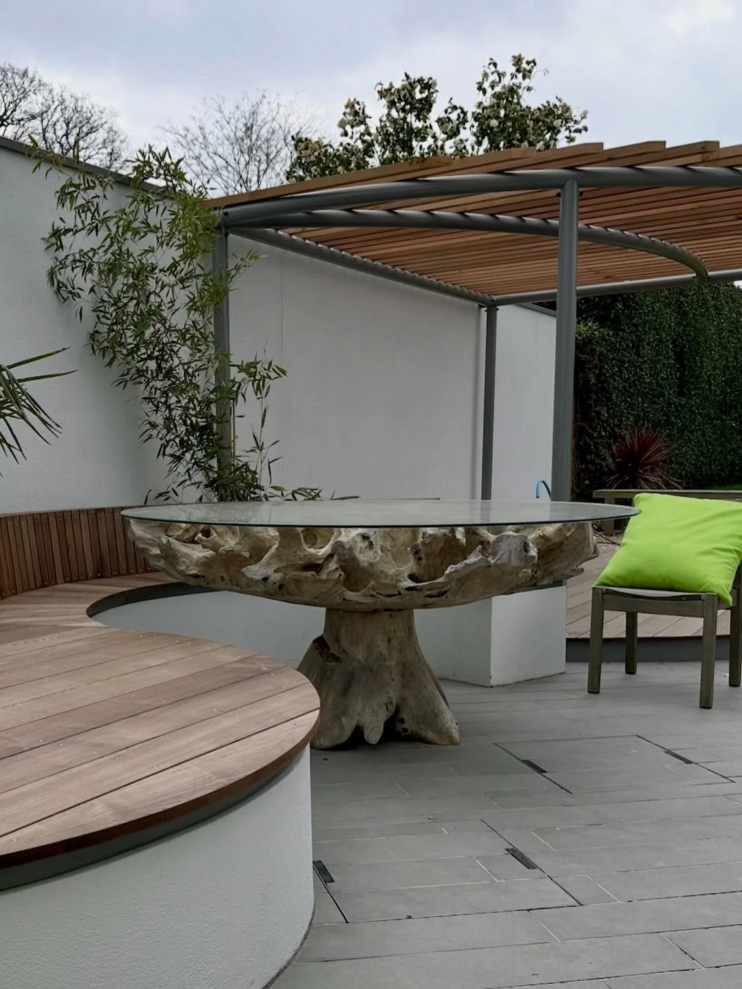 This recently completed garden brings together structure and flow, with a bespoke pergola and integrated bench designed in-house to anchor the space. Porcelain planks run through the scheme, adding texture and direction, while the embedded planters i