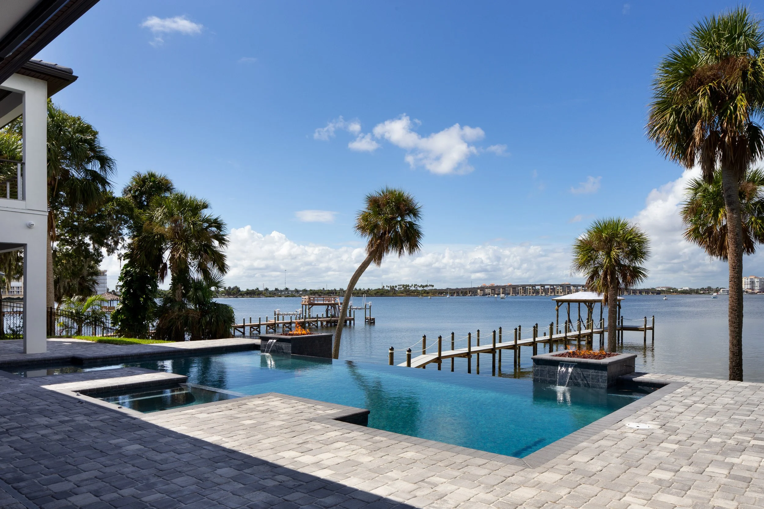 Ground view of a modern swimming pool overlooking a river, dock and causeway in the distance