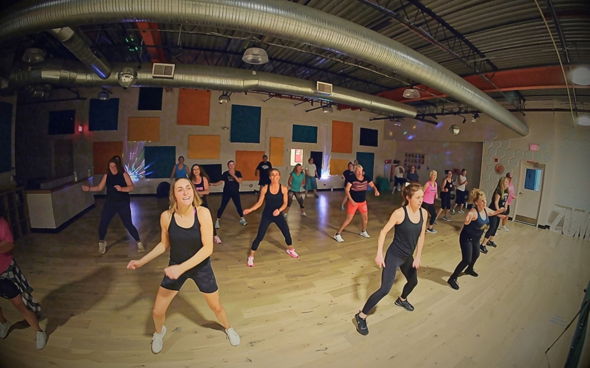 Members of BPDF dancing and smiling together in a lively group fitness class