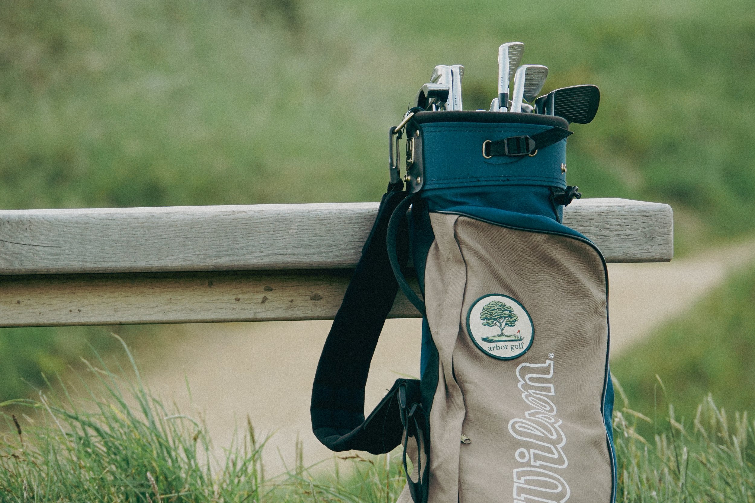 Golf bag with clubs on wooden bench outdoors