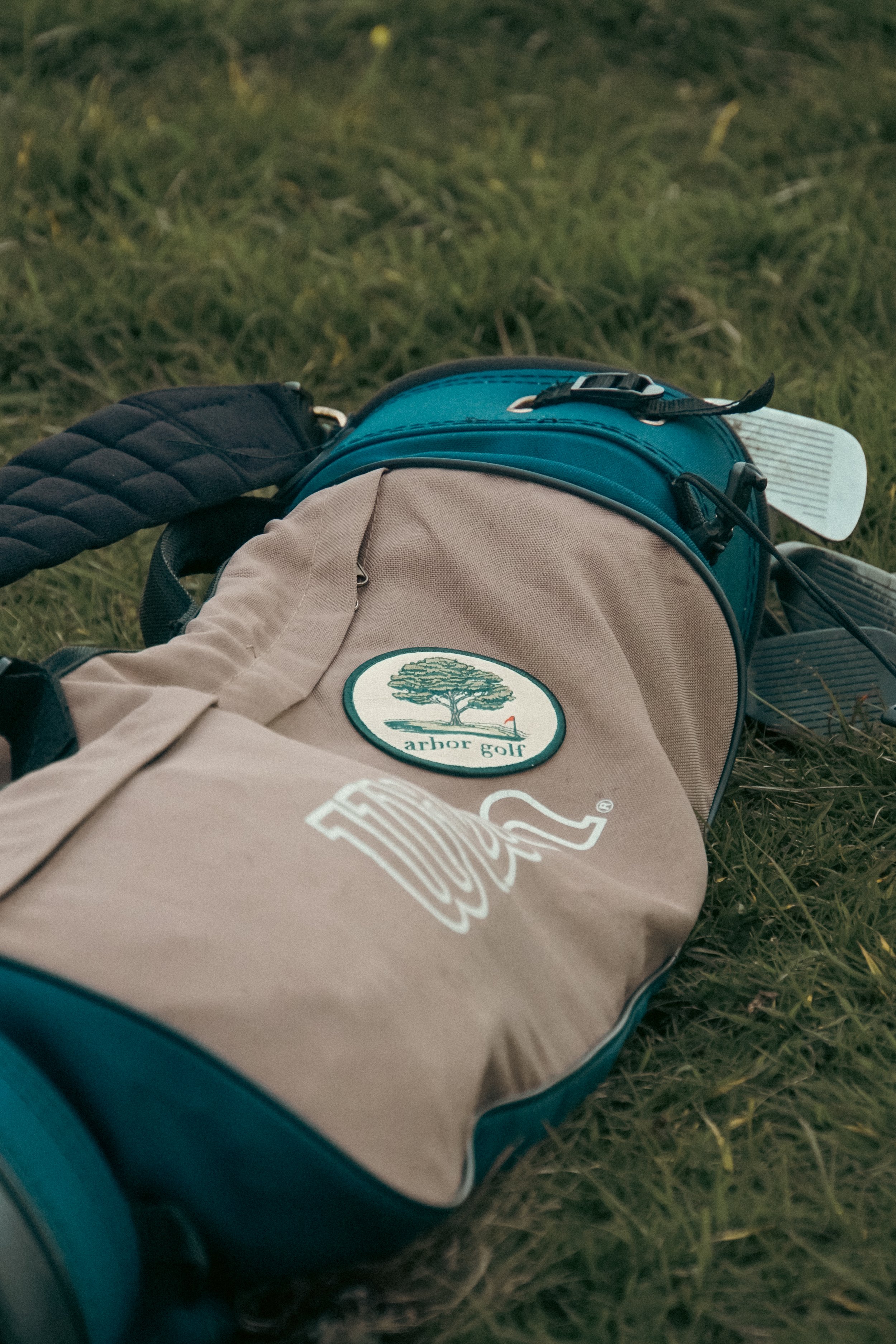 A golf bag lying on the grass with a partial logo visible.