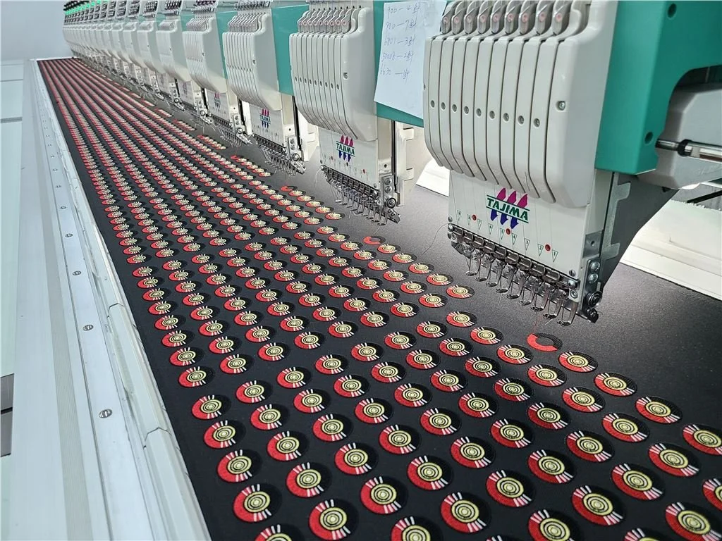 Row of embroidery machines producing pattern of circular patches on a textile surface.