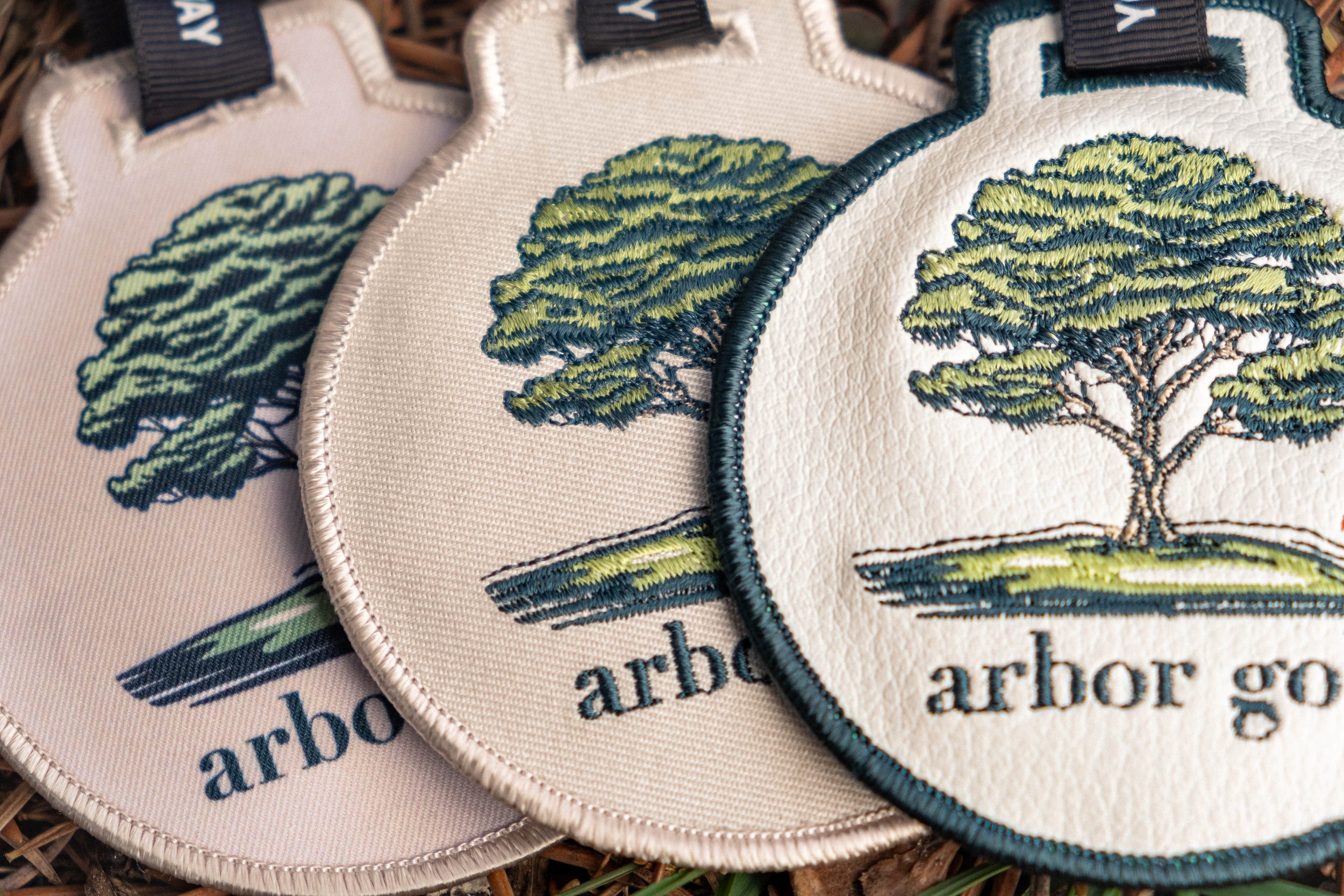 Three embroidered leather golf bag tags featuring a tree design and the text 'arbor golf.'