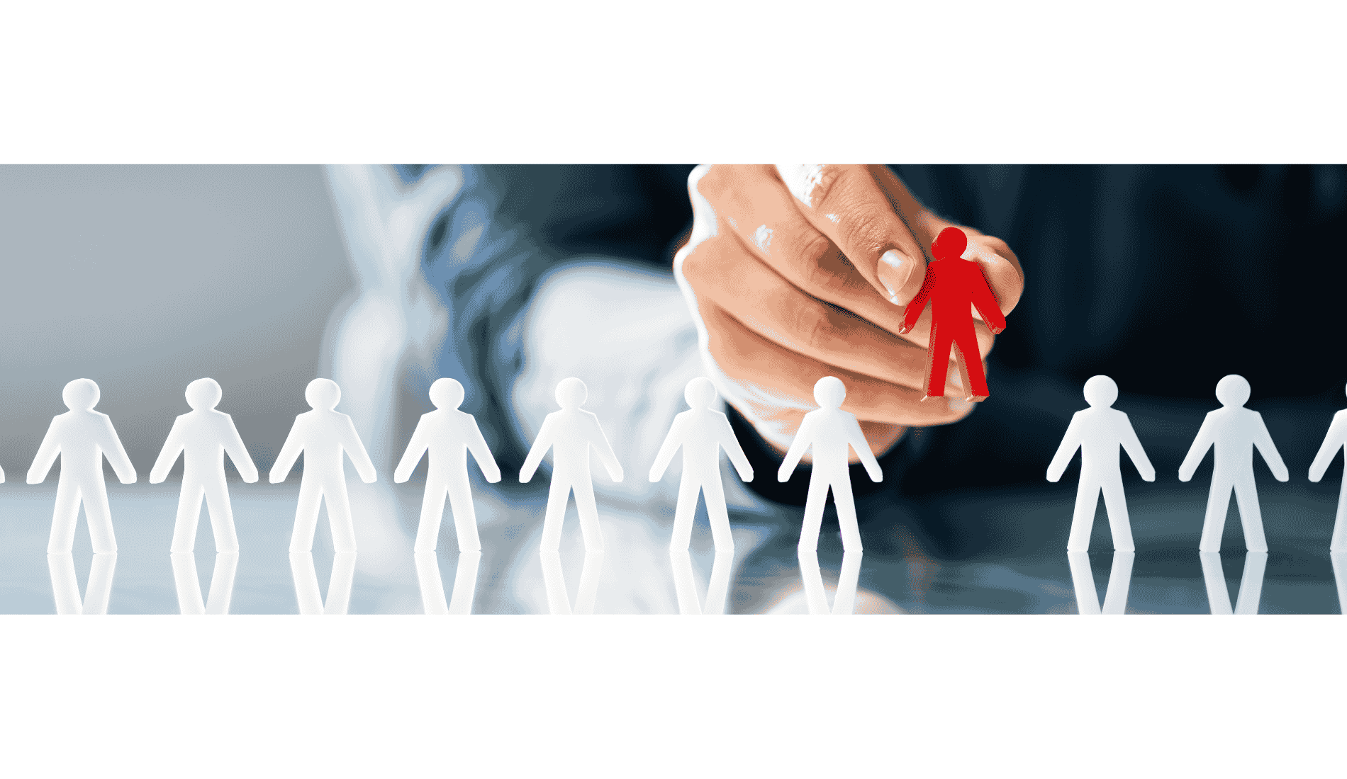 Une main tient une figurine rouge représentant une personne, en face d'une rangée de figurines blanches en forme de personnes.