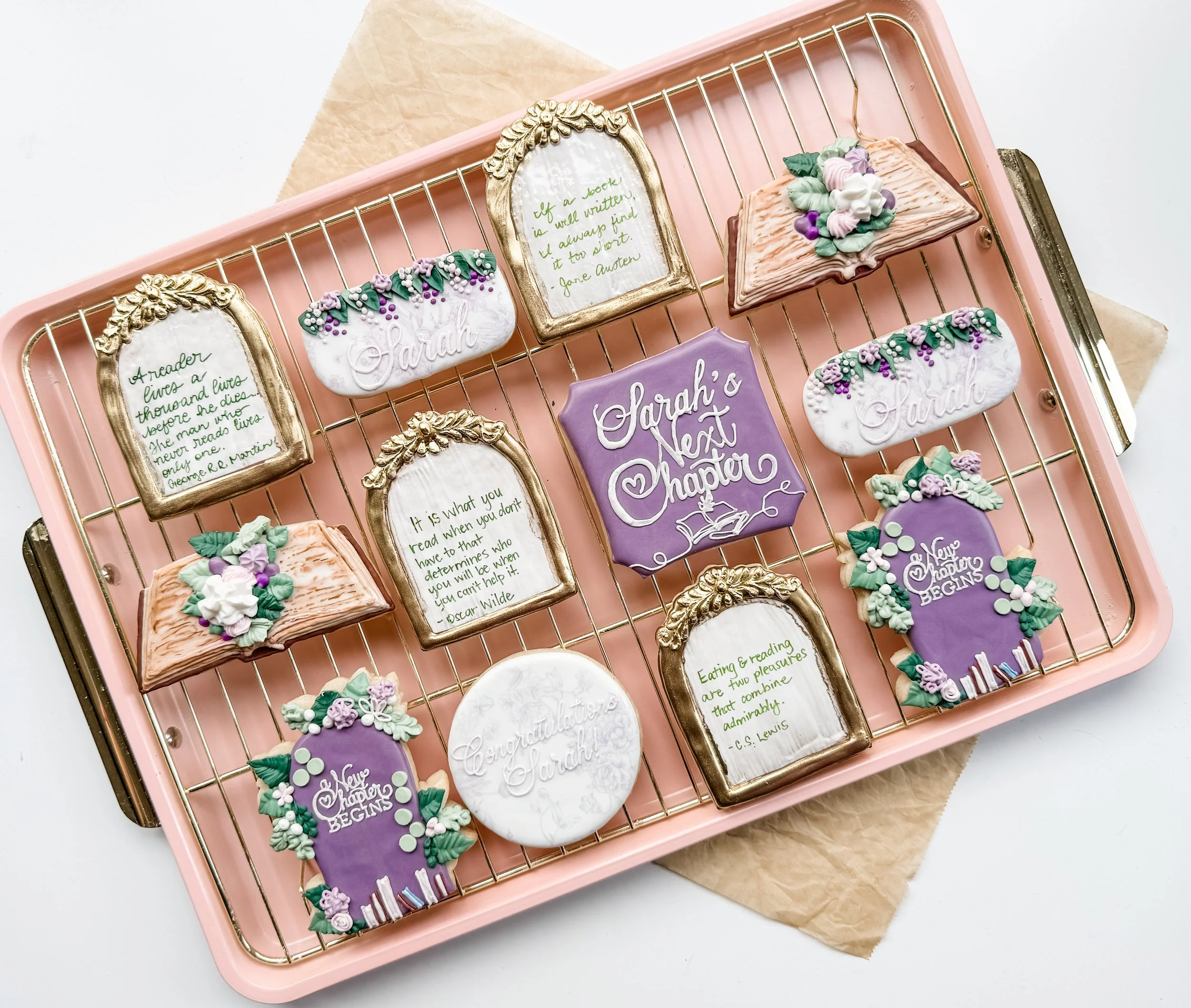 Decorative cookies with inspirational and congratulatory messages on a pink baking rack.