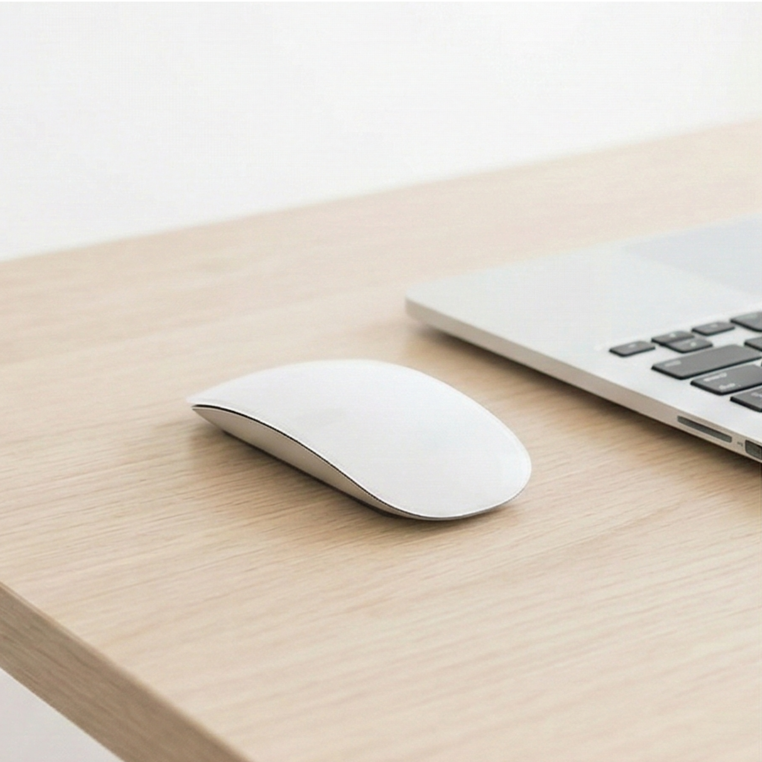 A clean, professional desk setup with a white computer mouse and laptop, representing Squarespace website management and custom builds that turn digital chaos into flow.