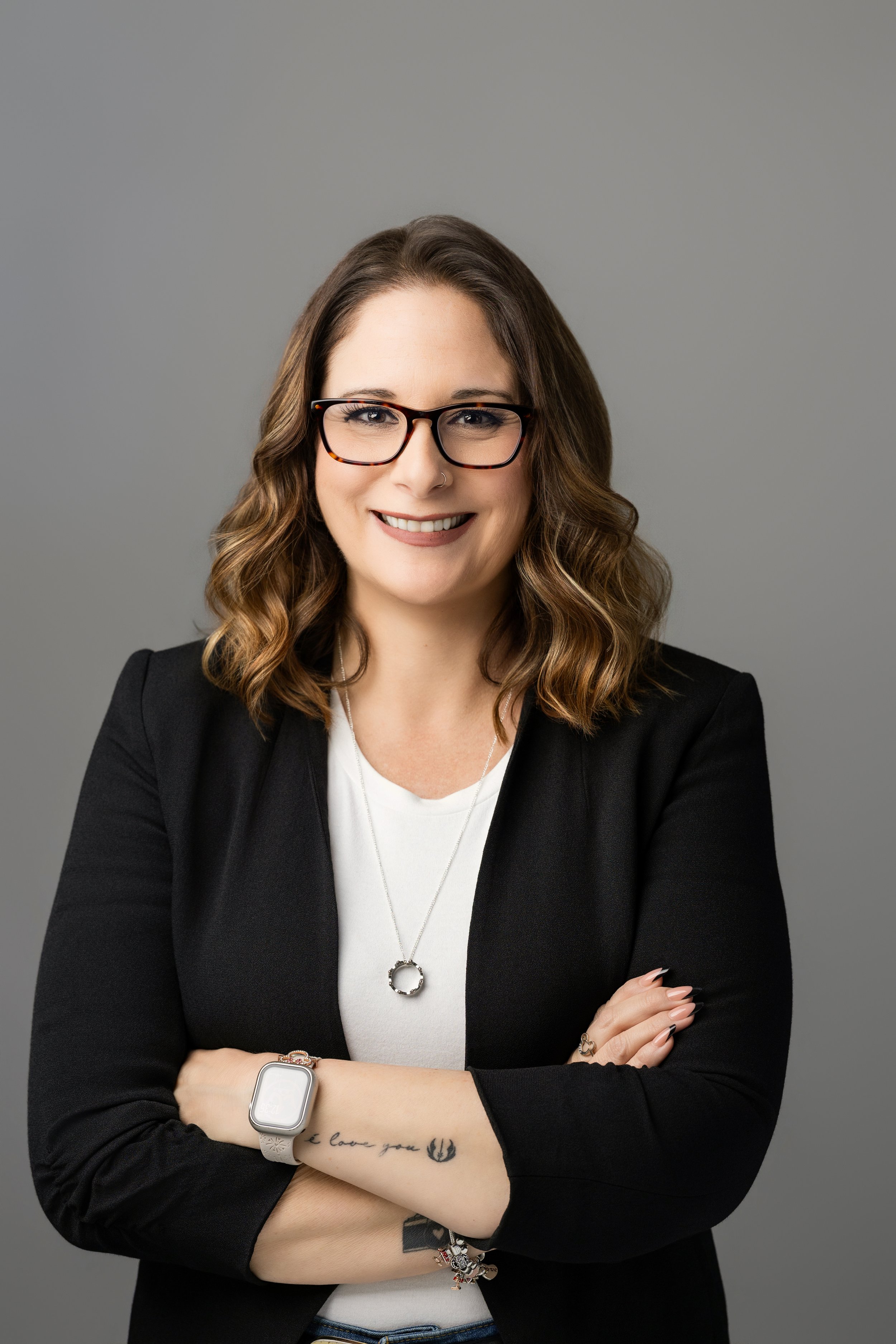 Small business operations and systems specialist in a white shirt and black blazer against a gray background